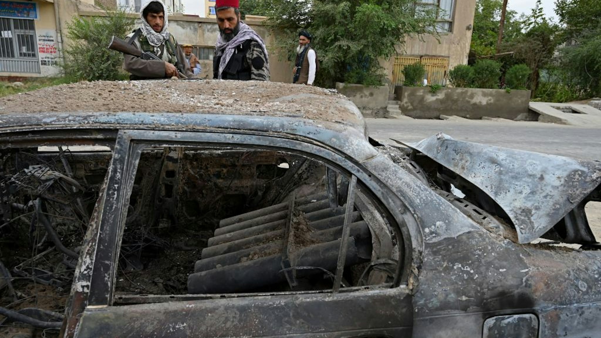 Taliban fighters investigate a damaged car after multiple rockets were fired in Kabul on August 30, 2021. - Rockets flew across the Afghan capital on August 30 as the US raced to complete its withdrawal from Afghanistan, with the evacuation of civilians all but over and terror attack fears high. (Photo by WAKIL KOHSAR / AFP) (Photo by WAKIL KOHSAR/AFP via Getty Images)