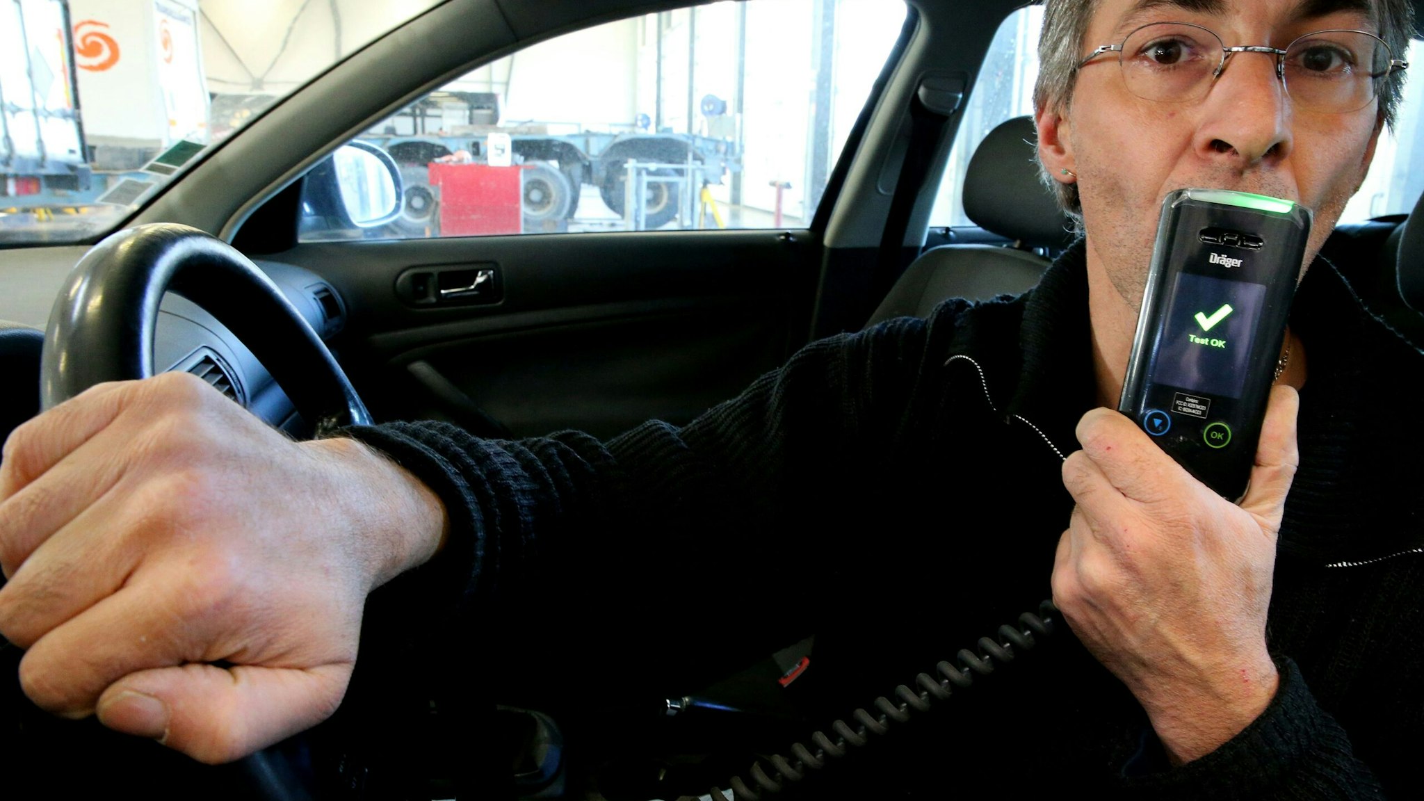 A man holds an electronic ethylotest device that prevents the start of the vehicle in case of positive control, in Reims, northeastern France, on December 1, 2016. This device is tested in several French departments from December 1 and will be mandatory for people in case of a positive test. The lettering on the display reads 'Test ok'. / AFP / François NASCIMBENI