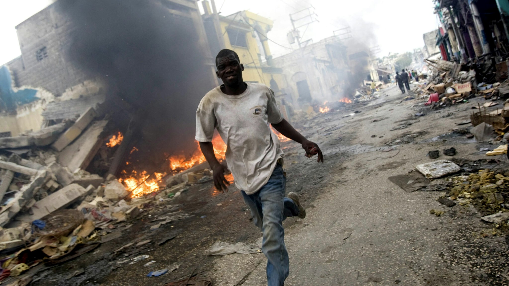 PORT-AU-PRINCE, HAITI - JANUARY 25: In this handout image provided by the United Nations Stabilization Mission in Haiti (MINUSTAH), A man runs besides a fire in downtown on January 25, 2010 in Port-au-Prince, Haiti. Haiti is trying to recover from a powerful 7.0-strong earthquake that struck on January 12 and devastated the country, displacing millions and killing tens of thousands.