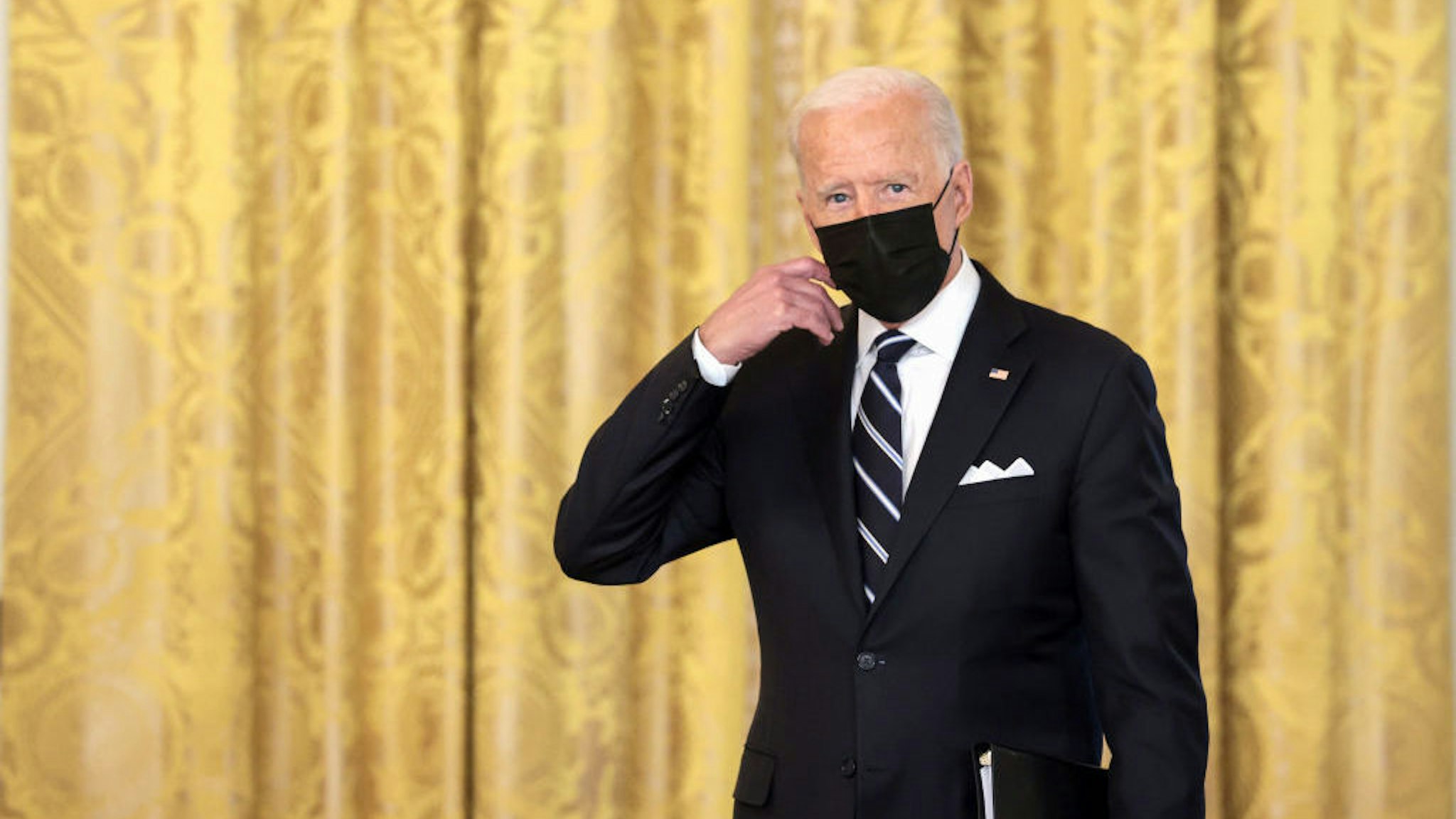 WASHINGTON, DC - AUGUST 18: U.S. President Joe Biden removes his face mask as he arrives to deliver remarks on the COVID-19 response and the vaccination program in the East Room of the White House on August 18, 2021 in Washington, DC. During his remarks, President Biden announced that he is ordering the United States Department of Health and Human Services to require nursing homes to have vaccinated staff in order for them to receive Medicare and Medicaid funding. The President also announced that Americans would be able to receive a third booster shot against Covid-19. (Photo by Anna Moneymaker/Getty Images)