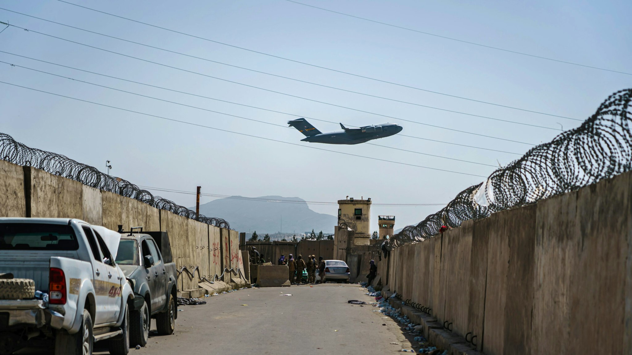 KABUL, AFGHANISTAN -- AUGUST 29, 2021: A C-17 Globemaster takes off as Taliban fighters secure the outer perimeter, alongside the American controlled side of of the Hamid Karzai International Airport in Kabul, Afghanistan, Sunday, Aug. 29, 2021.