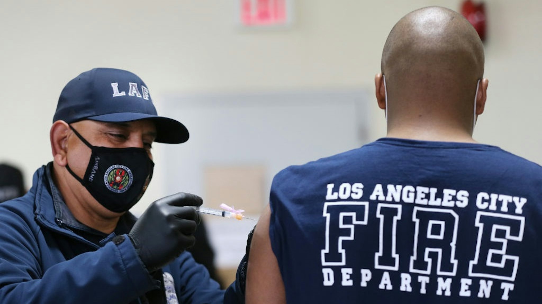 LOS ANGELES, CALIFORNIA - JANUARY 29: A Los Angeles Fire Department (LAFD) firefighter receives a Moderna COVID-19 vaccination dose from firefighter Michael Perez (L) at a fire station on January 29, 2021 in Los Angeles, California.