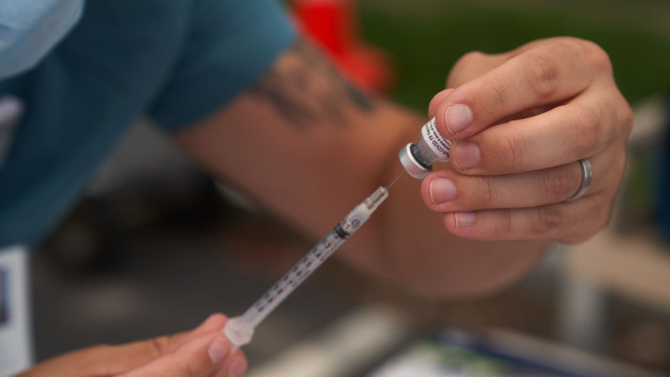 A healthcare worker prepares a dose of the Pfizer-BioNTech Covid-19 vaccine during a vaccination event at a school in Boston, Massachusetts, U.S., on Monday, August 16, 2021. With the highly contagious Delta variant sending more children to hospitals, a dozen states now require K-12 students to wear masks, while another handful bar such mandates.