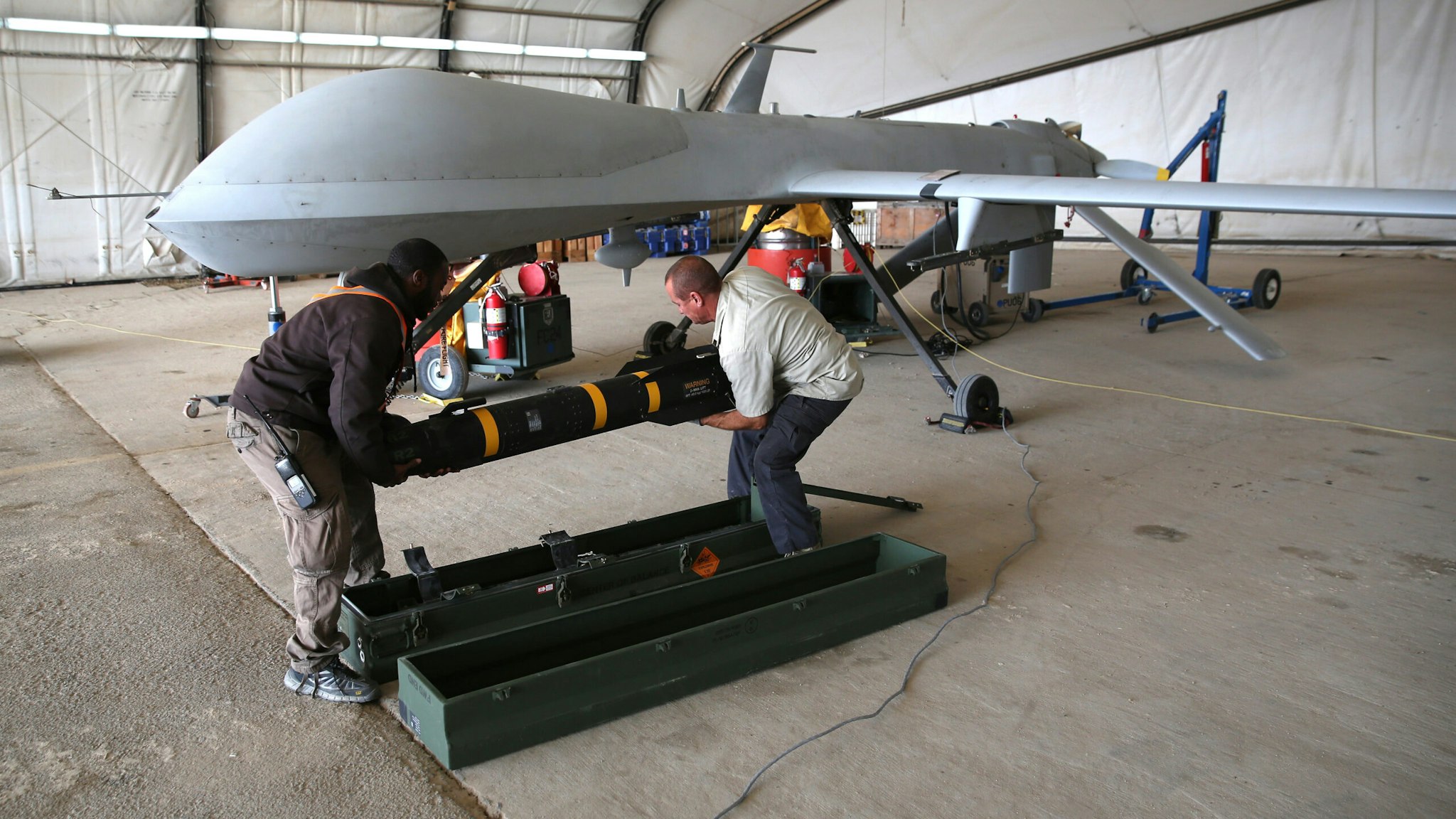 UNSPECIFIED, UNSPECIFIED - JANUARY 07: Contract workers load a Hellfire missile onto a U.S. Air Force MQ-1B Predator unmanned aerial vehicle (UAV), at a secret air base in the Persian Gulf region on January 7, 2016. The U.S. military and coalition forces use the base, located in an undisclosed location, to launch drone airstrikes against ISIL in Iraq and Syria, as well as to distribute cargo and transport troops supporting Operation Inherent Resolve. The Predators at the base are operated and maintained by the 46th Expeditionary Reconnaissance Squadron, currently attached to the 386th Air Expeditionary Wing.