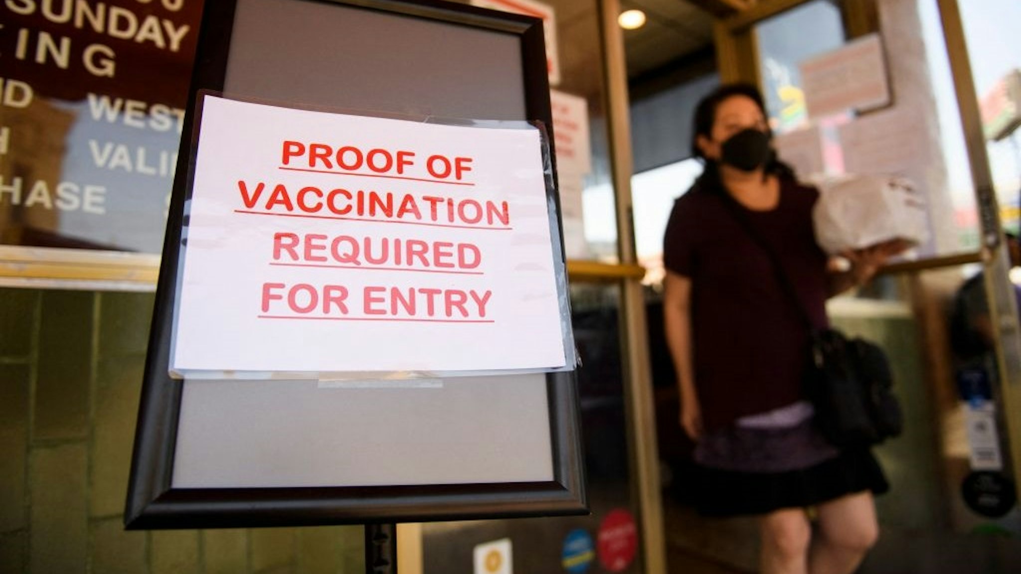 A sign stating proof of a Covid-19 vaccination is required is displayed outside of Langer's Deli in Los Angeles, California on August 7, 2021.