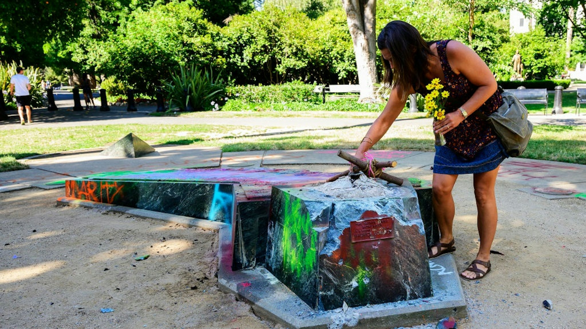 Devout Catholic Audrey Ortega creates a memorial at the former site of a statue memorializing Father Junipero Serra, a Spanish priest and friar who founded missions along California's coast in the 1700s, in Capitol Park on Sunday, July 5, 2020.