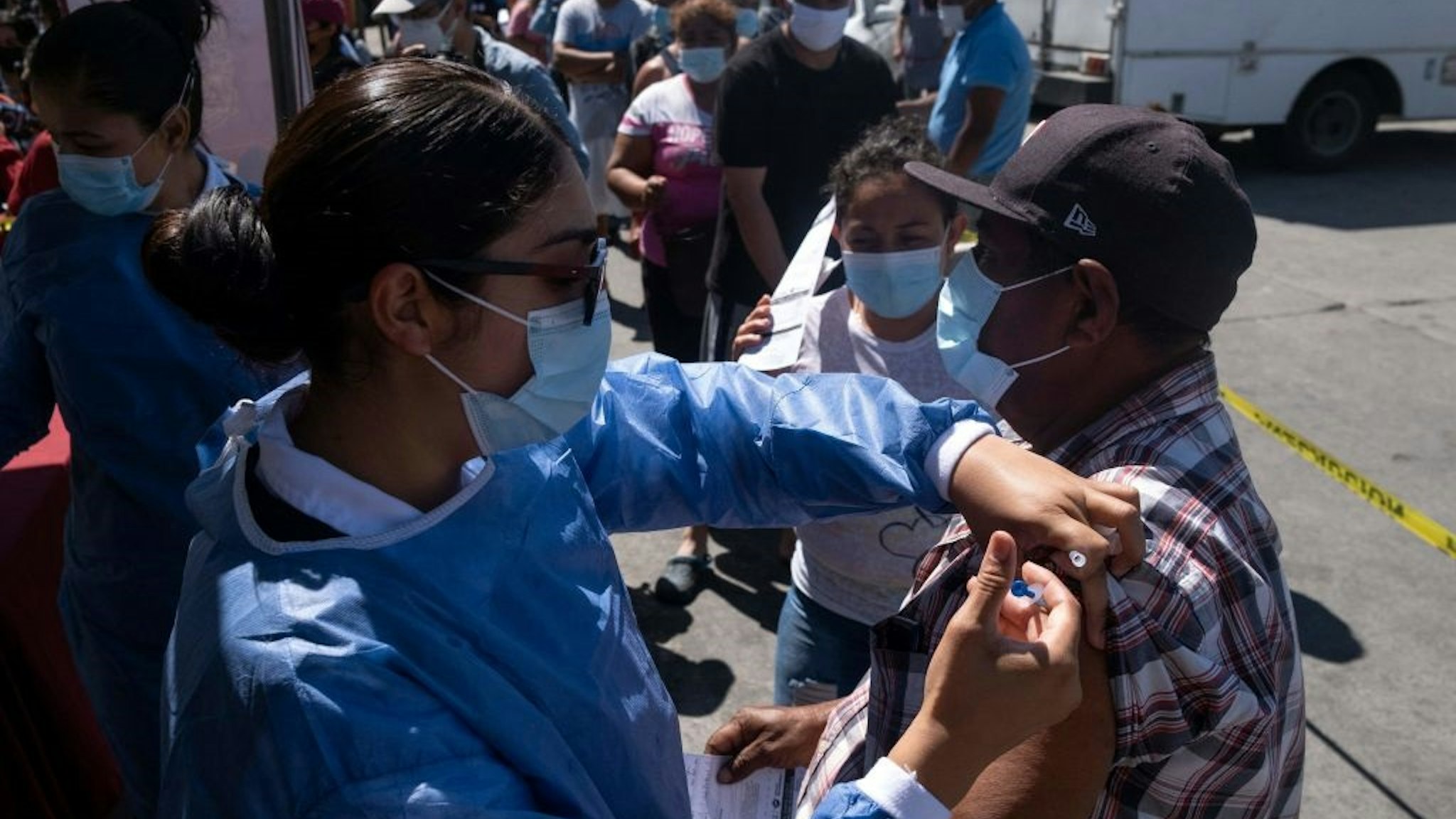 An asylum seeker camping at El Chaparral crossing port is vaccinated against COVID-19 in Tijuana, Baja California state, Mexico, on the border with the US, on August 3, 2021.