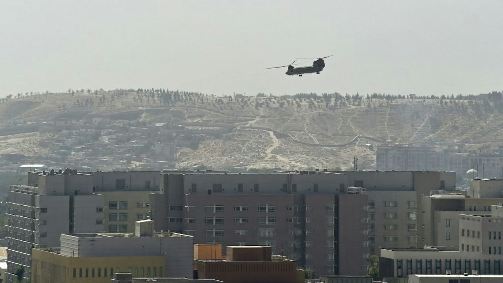 TOPSHOT - A US military helicopter is pictured flying above the US embassy in Kabul on August 15, 2021. (Photo by Wakil KOHSAR / AFP) (Photo by WAKIL KOHSAR/AFP via Getty Images)