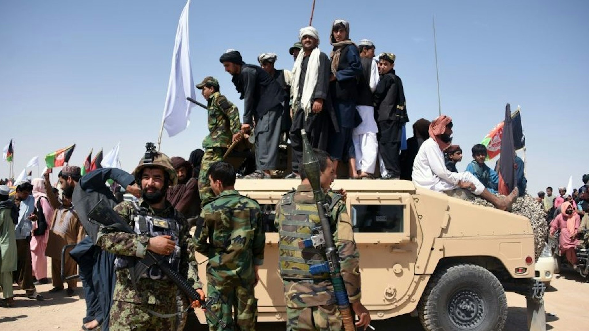 In this photo taken on June 17, 2018, Afghan Taliban militants and residents stand on a armoured Humvee vehicle of the Afghan National Army (ANA) as they celebrate a ceasefire on the third day of Eid in Maiwand district of Kandahar province. - Extraordinary scenes of Afghan Taliban and security forces spontaneously celebrating a historic ceasefire showed many fighters on both sides were fed up with the conflict, raising hopes that peace in the war-torn country was possible, analysts said. (Photo by JAVED TANVEER / AFP) / TO GO WITH Afghanistan-unrest-ceasefire,FOCUS by Allison Jackson (Photo credit should read J