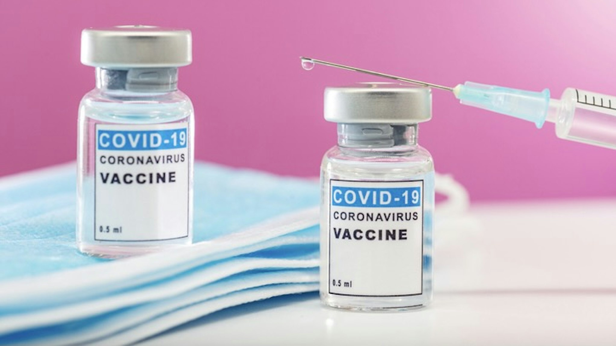 Vaccination concept. Close-up medical syringe with a vaccine. - stock photo Coronavirus vaccine in syringe. Macro image of needle and vaccine ampoules on pink background Stefan Cristian Cioata via Getty Images