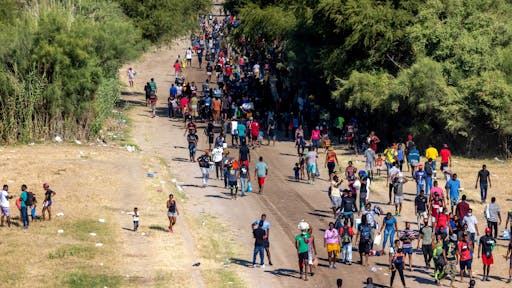 Large Migration Surge Crosses Rio Grande Into Del Rio, Texas DEL RIO, TX - SEPTEMBER 17: Migrants, mostly from Haiti, gather at a makeshift encampment under the International Bridge on the broder between Del Rio, TX and Acuña, MX on September 17, 2021 in Del Rio, Texas. The makeshift encampment has grown rapidly and officials are struggling to provide food, water, shelter, and sanitation, forcing between 8,000 and 12,000 migrants to walk across the Rio Grande several times each day for basic necessities.