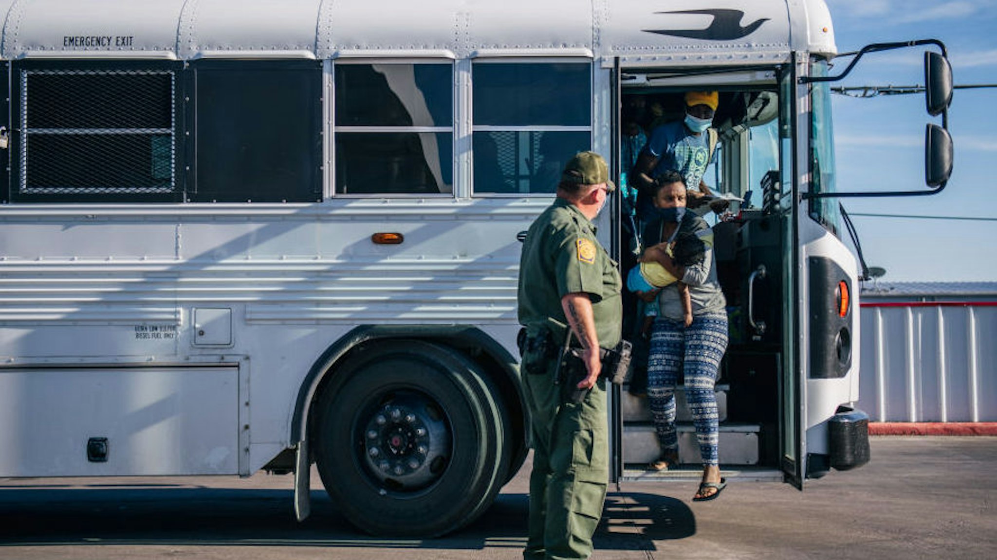 DEL RIO, TEXAS - SEPTEMBER 22: Migrants exit a Border Patrol bus and prepare to be received by the Val Verde Humanitarian Coalition after crossing the Rio Grande on September 22, 2021 in Del Rio, Texas. Thousands of immigrants, mostly from Haiti, seeking asylum have crossed the Rio Grande into the United States. Families are living in makeshift tents under the international bridge while waiting to be processed into the system. U.S. immigration authorities have been deporting planeloads of migrants directly to Haiti while others have crossed the Rio Grande back into Mexico.