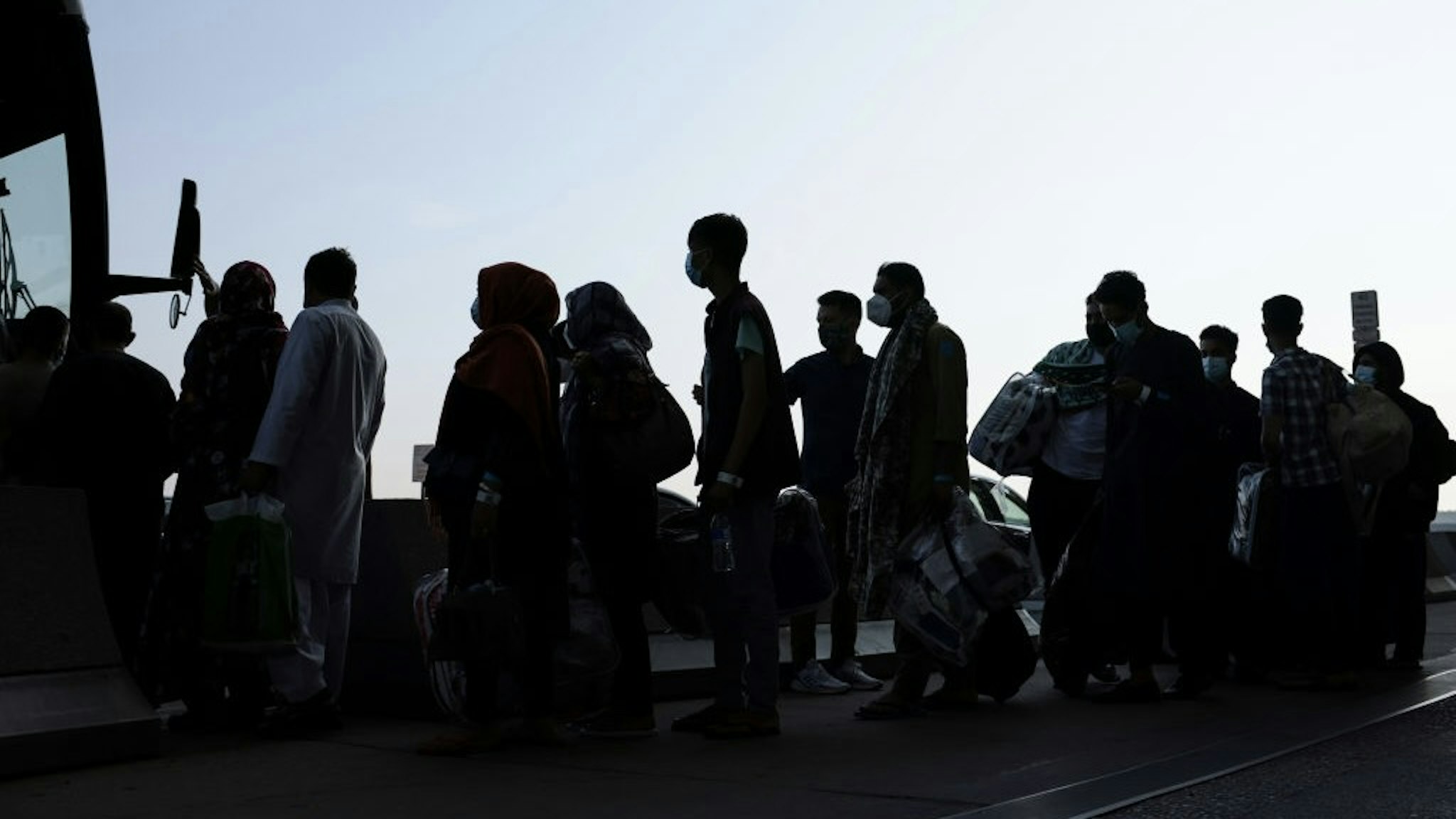 Afghan Refugees Arrive At Dulles Airport Outside Nation's Capital DULLES, VIRGINIA - AUGUST 25: People evacuated from Kabul Afghanistan wait to board a bus that will take them to a refugee processing center at the Dulles International Airport on August 25, 2021 in Dulles, Virginia. According to the U.S. Department of Defense, five evacuation flights from Kabul, Afghanistan have landed at the Dulles Airport carrying 1,200 Afghan refugees in last day. The White House also announced that since August 14, the U.S. has evacuated and facilitated the evacuation of approximately 82,300 people on US military and coalition flights. (Photo by Anna Moneymaker/Getty Images) Anna Moneymaker / Staff