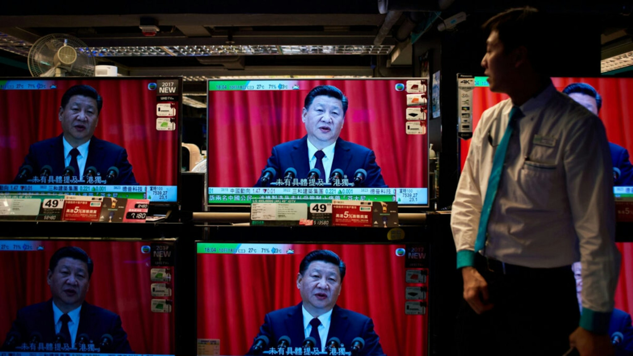 An electronics shop employee in Hong Kong on October 18, 2017 looks at television sets showing a news report on China's President Xi Jinping's speech at the opening session of the Chinese Communist Party's five-yearly Congress at the Great Hall of the People in Beijing.