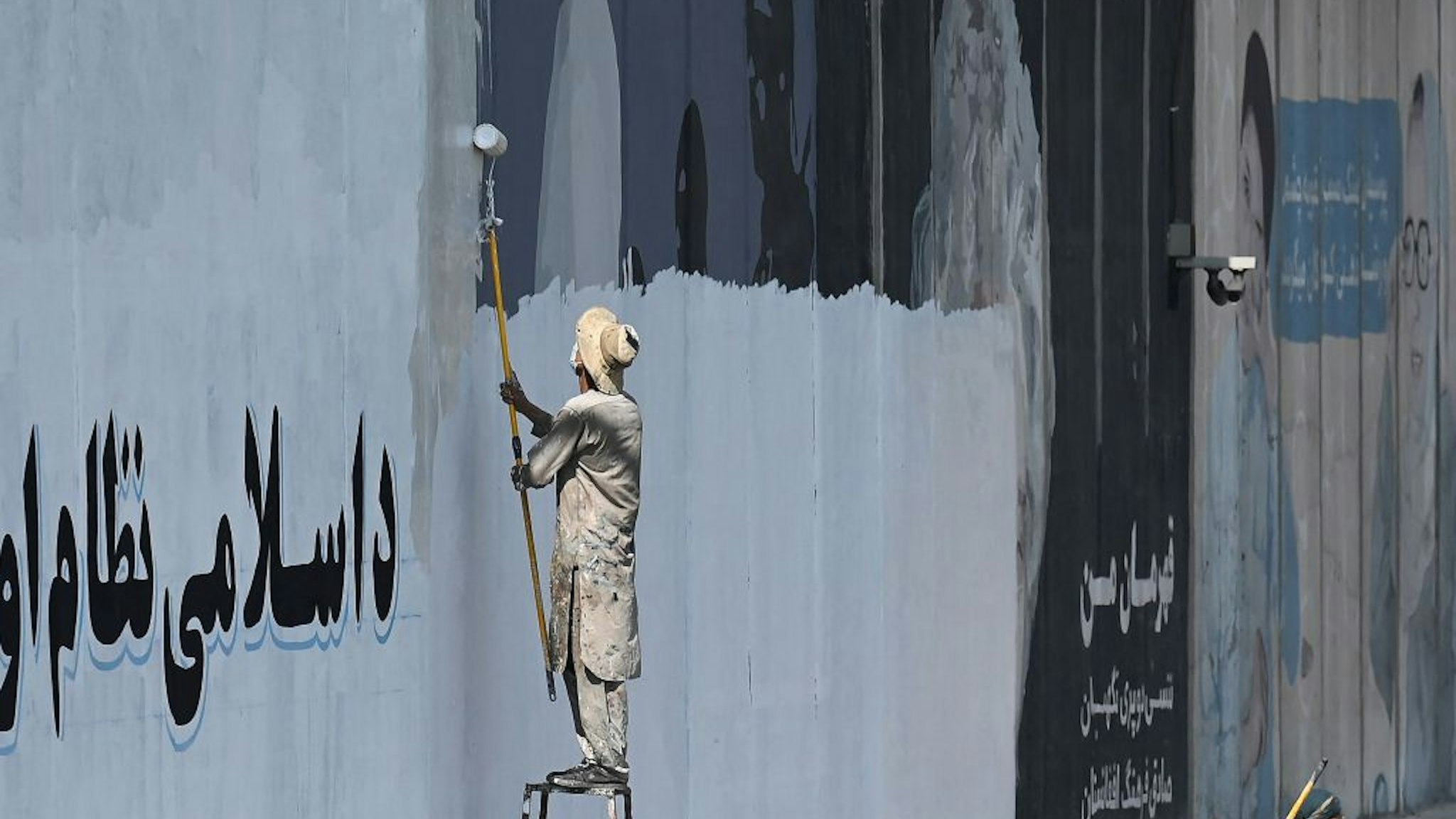 TOPSHOT - A man paints over murals on a concrete wall along a street in Kabul on September 4, 2021. - Within weeks of the Taliban taking the capital, many of the street art pieces have been painted over, replaced by drab propaganda slogans as the Islamist reimpose their austere vision on Afghanistan. (Photo by Aamir QURESHI / AFP) (Photo by AAMIR QURESHI/AFP via Getty Images)