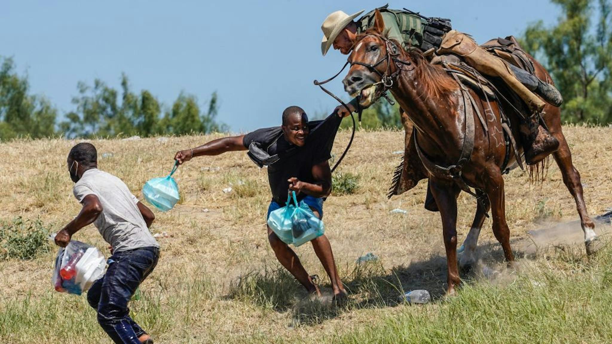 TOPSHOT-US-POLITICS-IMMIGRATION-TEXAS A United States Border Patrol agent on horseback tries to stop a Haitian migrant from entering an encampment on the banks of the Rio Grande near the Acuna Del Rio International Bridge in Del Rio, Texas on September 19, 2021.