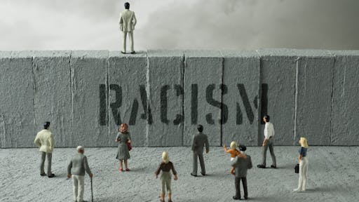 Racism in graffiti People figurines looking at the Racism warning on the wall. Uncertainty concept