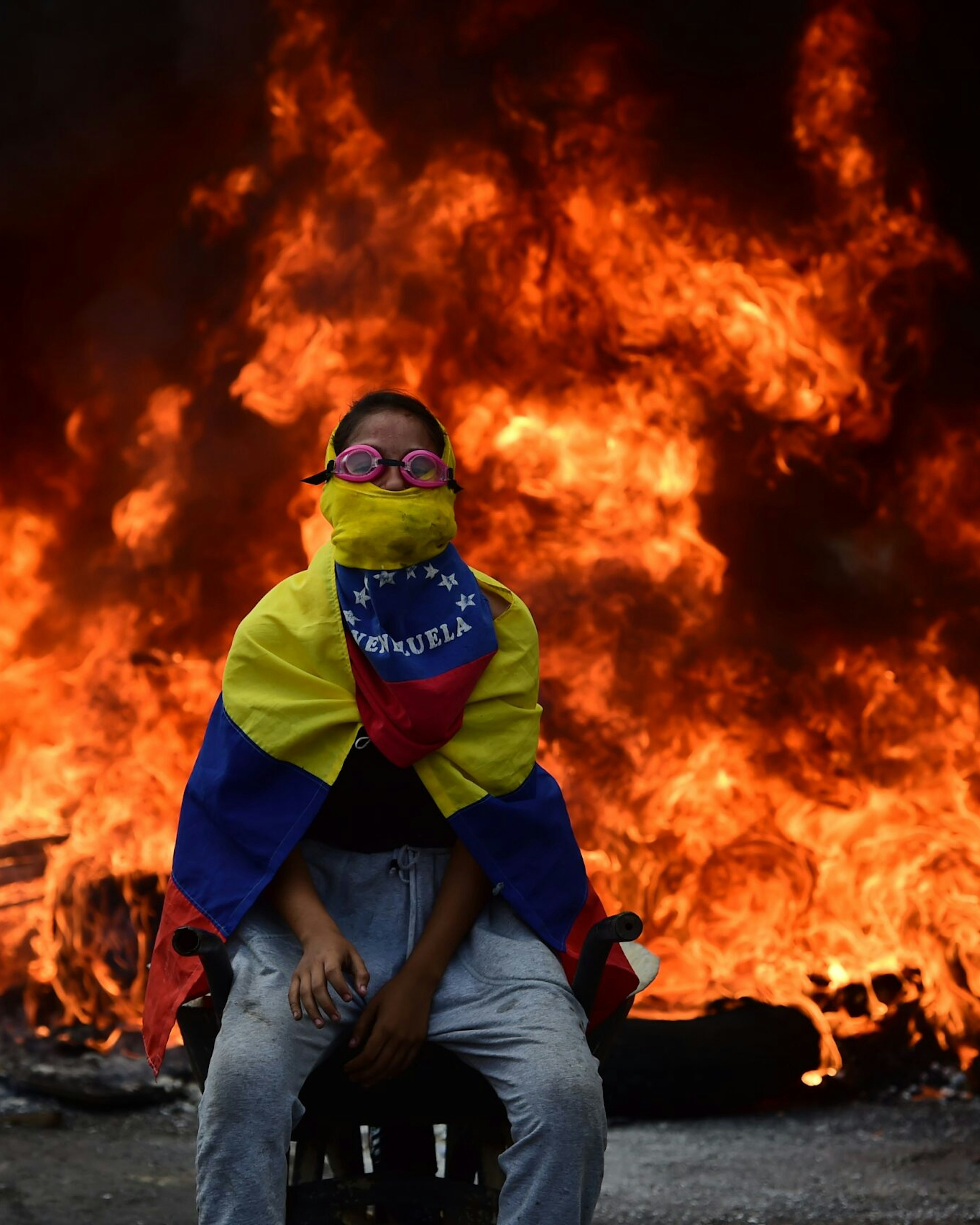 TOPSHOT - A Venezuelan opposition activist is backdropped by a burning barricade during a demonstration against President Nicolas Maduro in Caracas, on April 24, 2017.