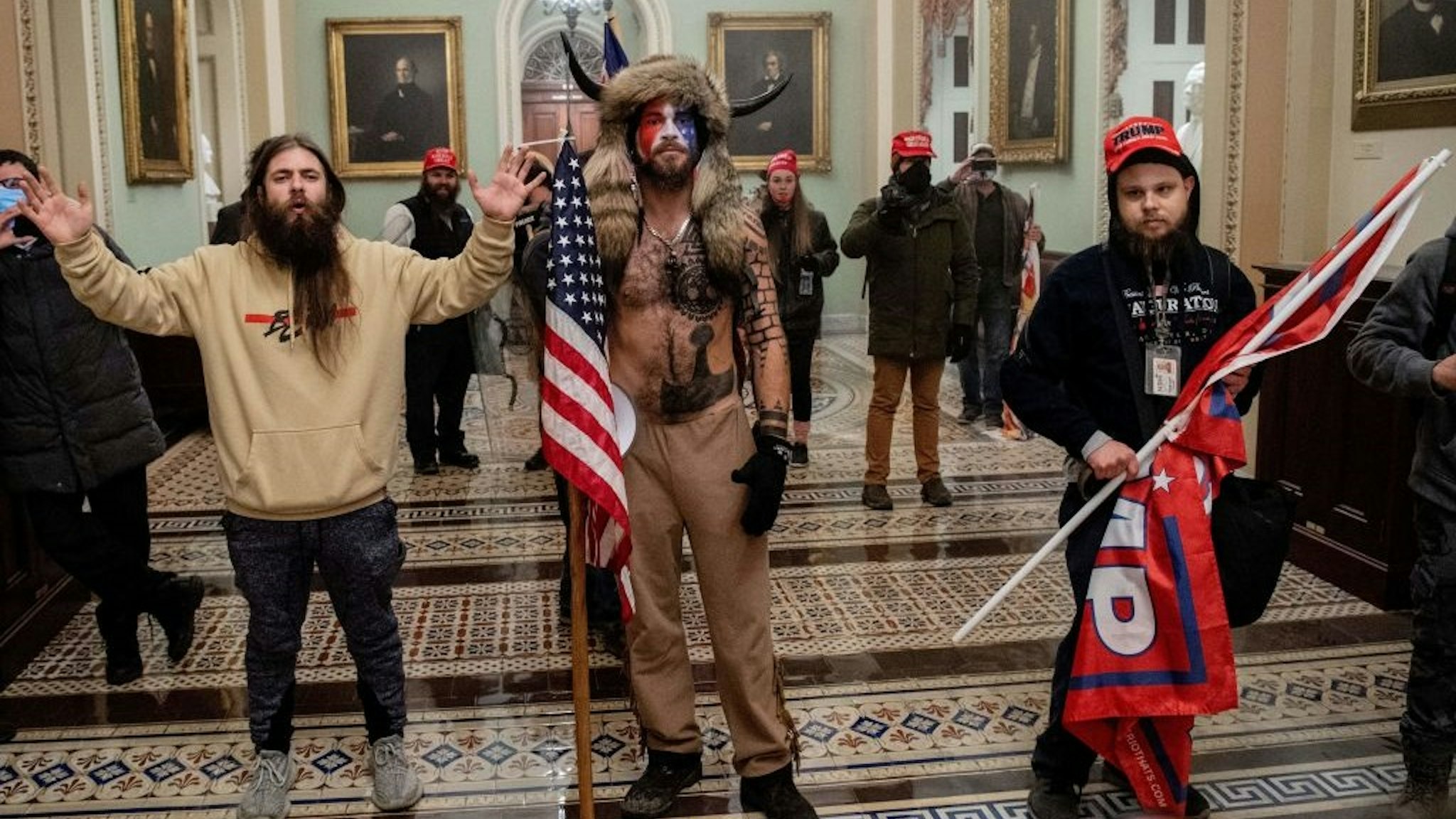 Supporters of US President Donald Trump, including Jake Angeli (C), a QAnon supporter known for his painted face and horned hat, enter the US Capitol on January 6, 2021, in Washington, DC.