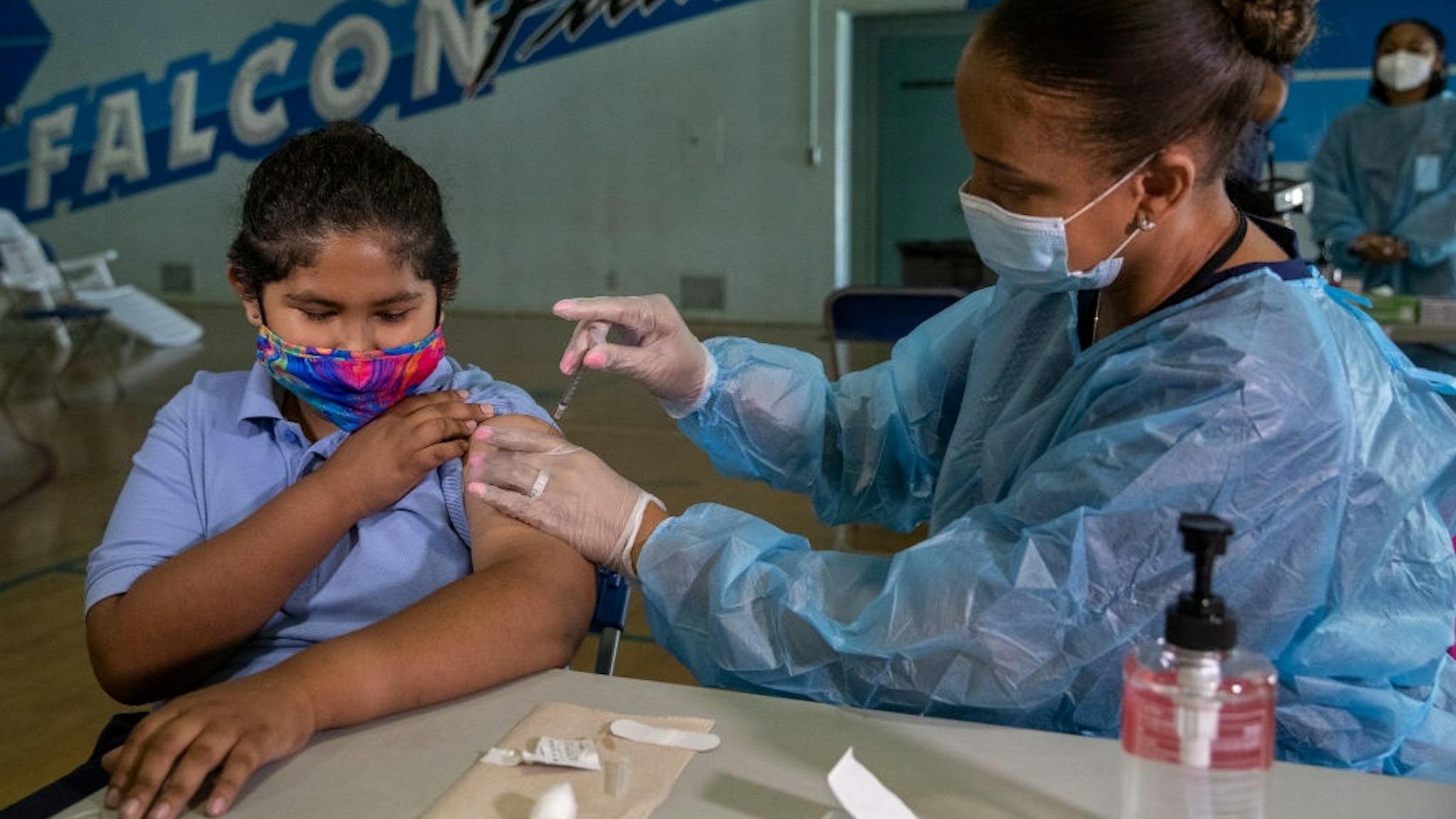 SAN FERNANDO, CA - AUGUST 30: Angel Macias, 12, a 7th grader at San Fernando Institute for Applied Media in San Fernando, receives the first dose of the Pfiizer vaccine from Tracy Jones, a licensed vocational nurse.