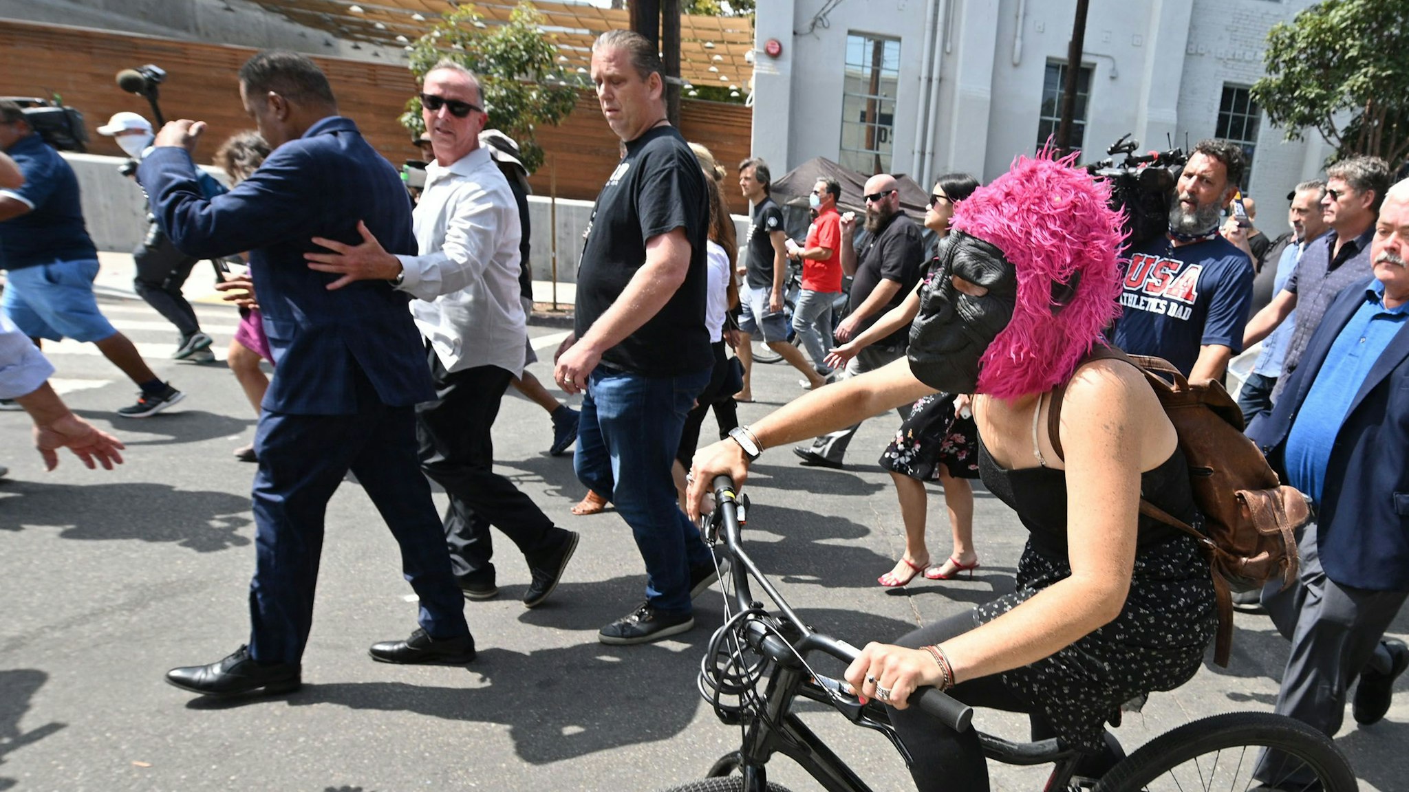 A woman wearing a guerilla mask follows conservative talk show host and gubernatorial recall candidate Larry Elder (L) (back to camera) as he walks along streets lined with tents of unhoused people, in the Venice neighborhood of Los Angeles, California, September 8, 2021 ahead of the special recall election. - The recall election, which will be held on September 14, 2021, asks voters to respond two questions: whether Governor Gavin Newsom, a Democratic, should be recalled from the office of governor, and who should succeed Newsom if he is recalled. Forty-six candidates, including nine Democrats and 24 Republicans, are looking to take Newsom's place as the governmental leader of California.