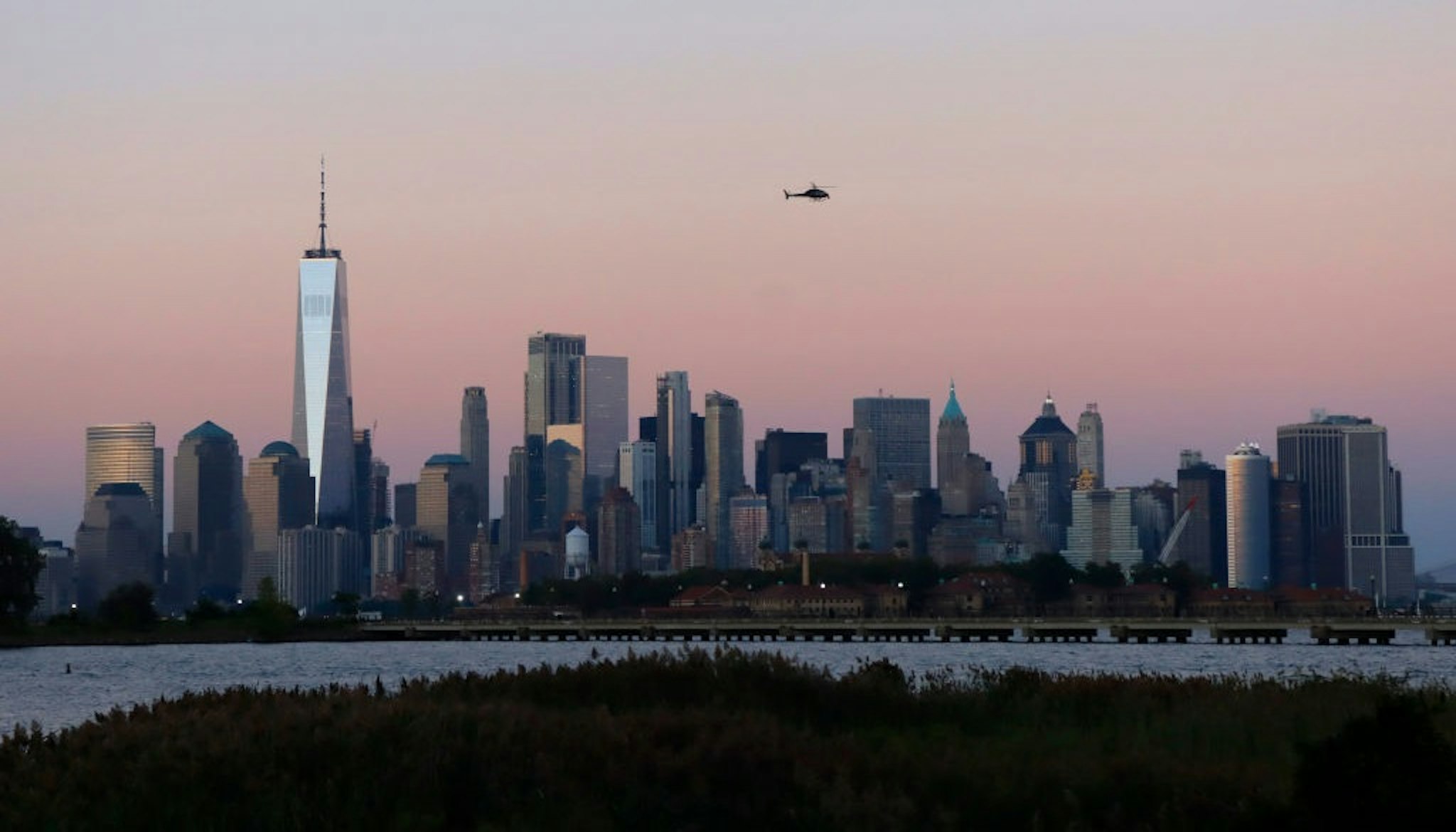 JERSEY CITY, NJ - SEPTEMBER 7: A helicopter flies over the skyline of lower Manhattan and One World Trade Center as the sun sets in New York City on September 7, 2021 as seen from Jersey City, New Jersey.