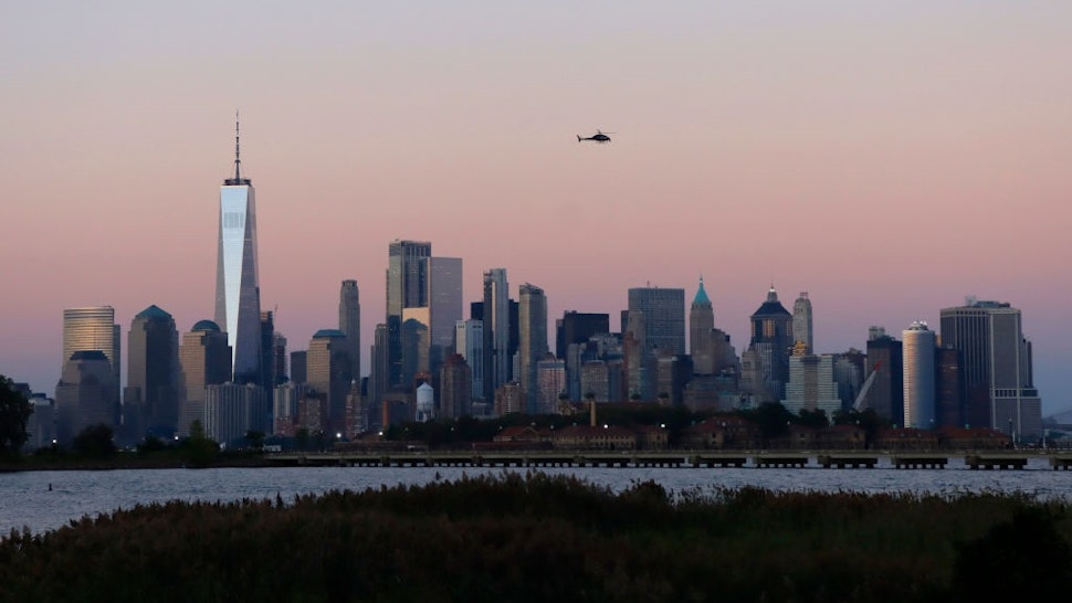 JERSEY CITY, NJ - SEPTEMBER 7: A helicopter flies over the skyline of lower Manhattan and One World Trade Center as the sun sets in New York City on September 7, 2021 as seen from Jersey City, New Jersey.