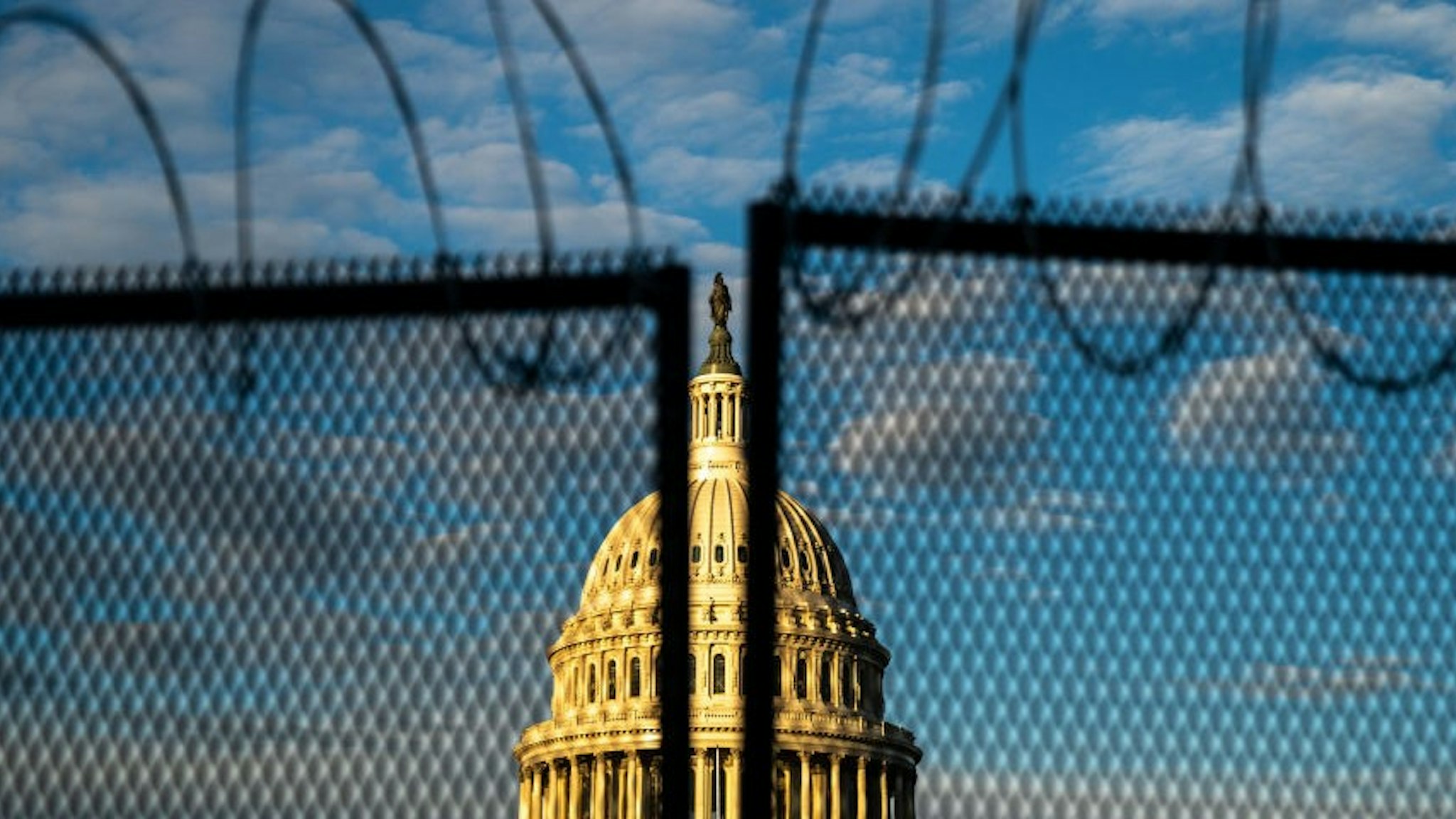 WASHINGTON, DC - JANUARY 16: Barbed wire, is seen atop security fencing, with the dome of the U.S. Capitol Building on Saturday, Jan. 16, 2021 in Washington, DC. After last week's riots and security breach at the U.S. Capitol Building, the FBI has warned of additional threats in the nation's capital and across all 50 states. (
