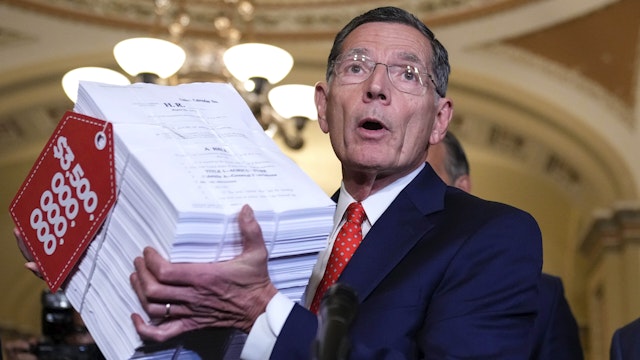 WASHINGTON, DC - SEPTEMBER 28: Senate Minority Leader Mitch McConnell (R-KY) looks on as Sen. John Barrasso (R-WY) holds up a visual aide to represent the Democrats' $3.5 trillion budget reconciliation package as he speaks to reporters after a lunch meeting with Senate Republicans at the U.S. Capitol on September 28, 2021 in Washington, DC. Senator McConnell said on Tuesday that his Republican caucus will not assist Democrats in raising the debt ceiling.