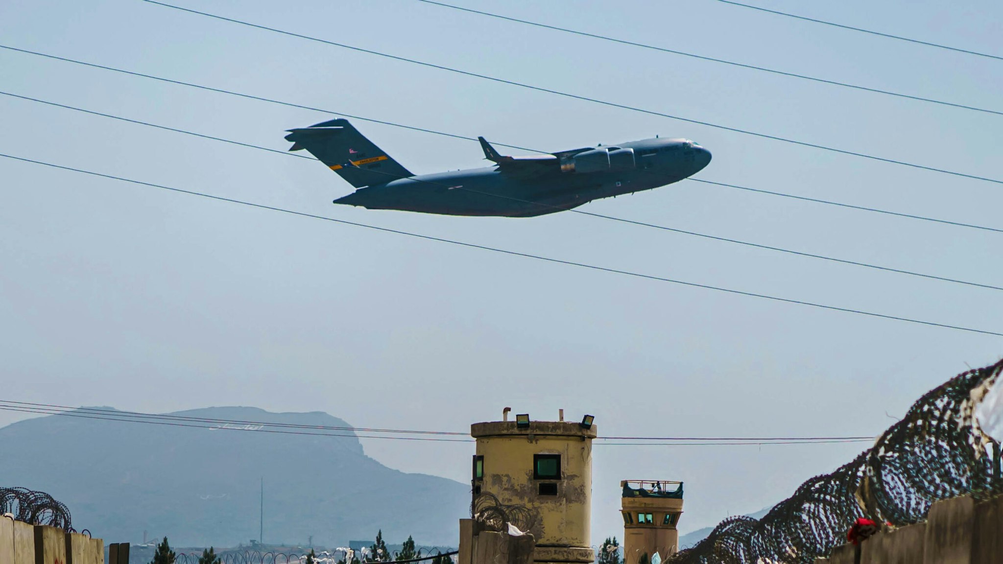 KABUL, AFGHANISTAN -- AUGUST 29, 2021: A C-17 Globemaster takes off as Taliban fighters secure the outer perimeter, alongside the American controlled side of of the Hamid Karzai International Airport in Kabul, Afghanistan, Sunday, Aug. 29, 2021.