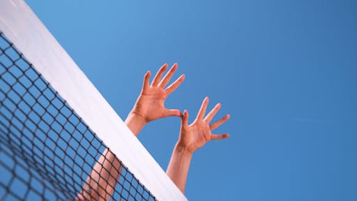 CLOSE UP: Unrecognizable athletic woman’s hands stretch over the volleyball net. woman spiking volleyball