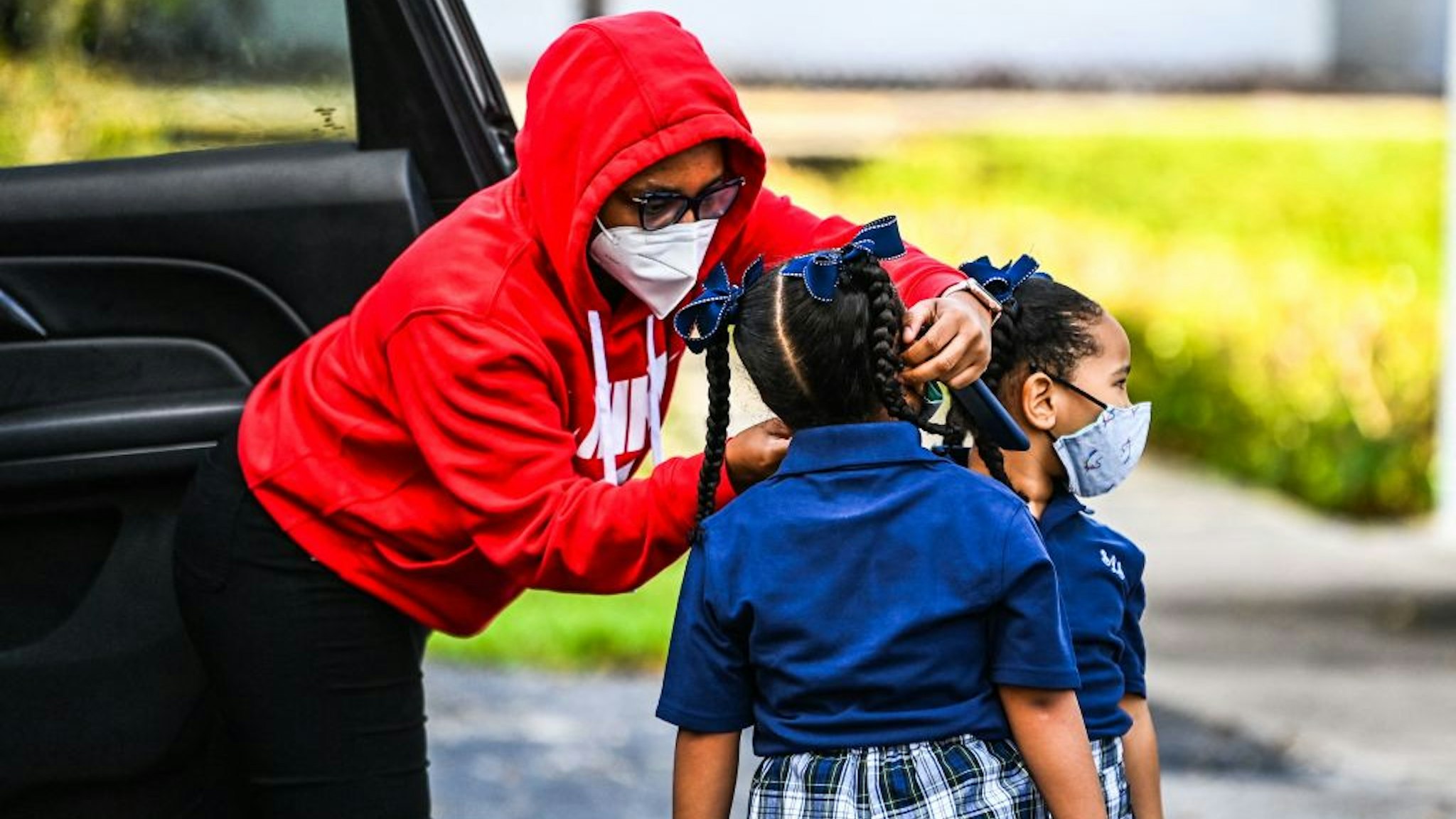 A mother adjusts the facemask of her child as she enters the St. Lawrence Catholic School on the first day of school after summer vacation in north of Miami, on August 18, 2021. (Photo by CHANDAN KHANNA / AFP) (Photo by CHANDAN KHANNA/AFP via Getty Images)
