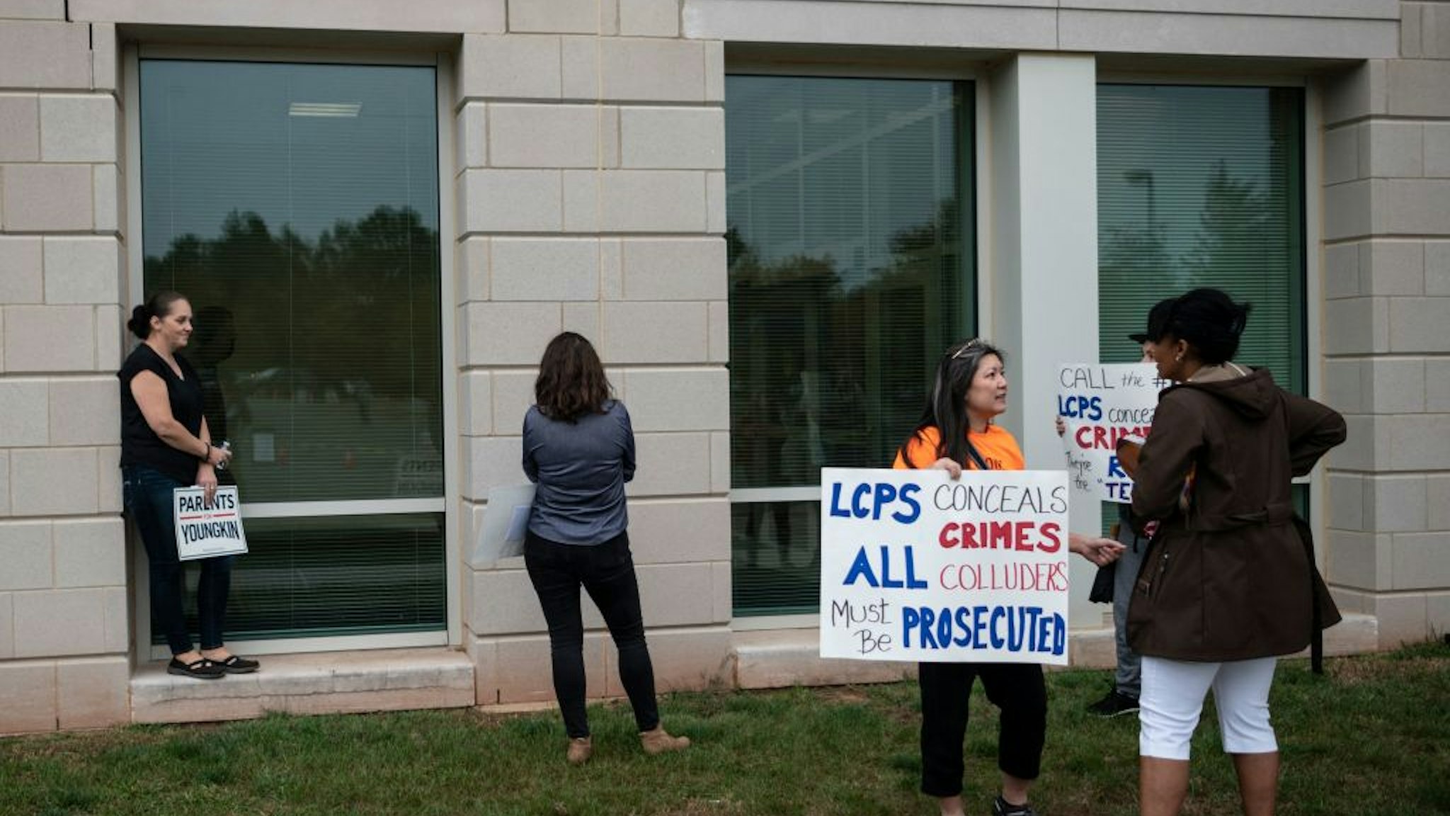 Protesters and activists hold signs as they stand outside a Loudoun County Public Schools (LCPS) board meeting in Ashburn, Virginia on October 12, 2021.