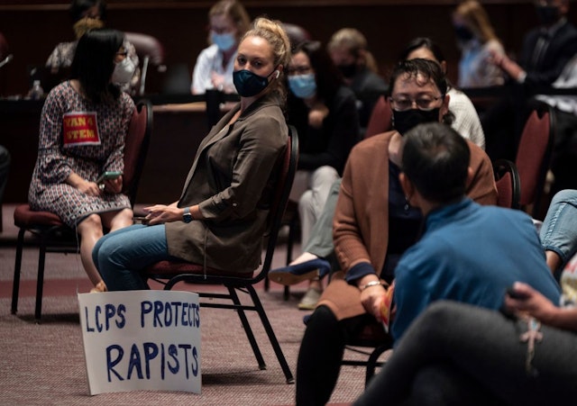 A woman sits with her sign during a Loudoun County Public Schools (LCPS) board meeting in Ashburn, Virginia on October 12, 2021.