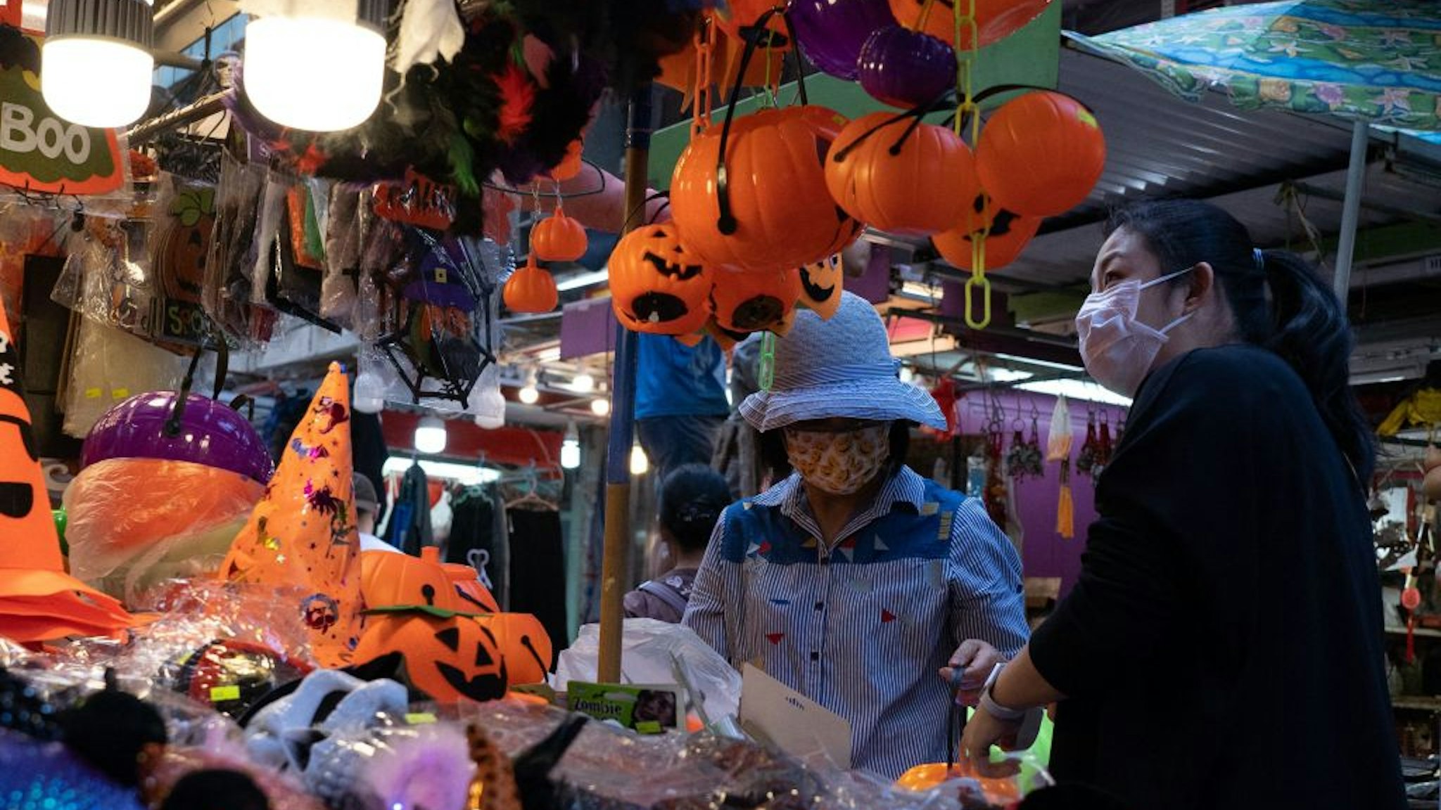 A customer (R) browses through seasonal halloween props at a stall in Hong Kong on October 16, 2021.