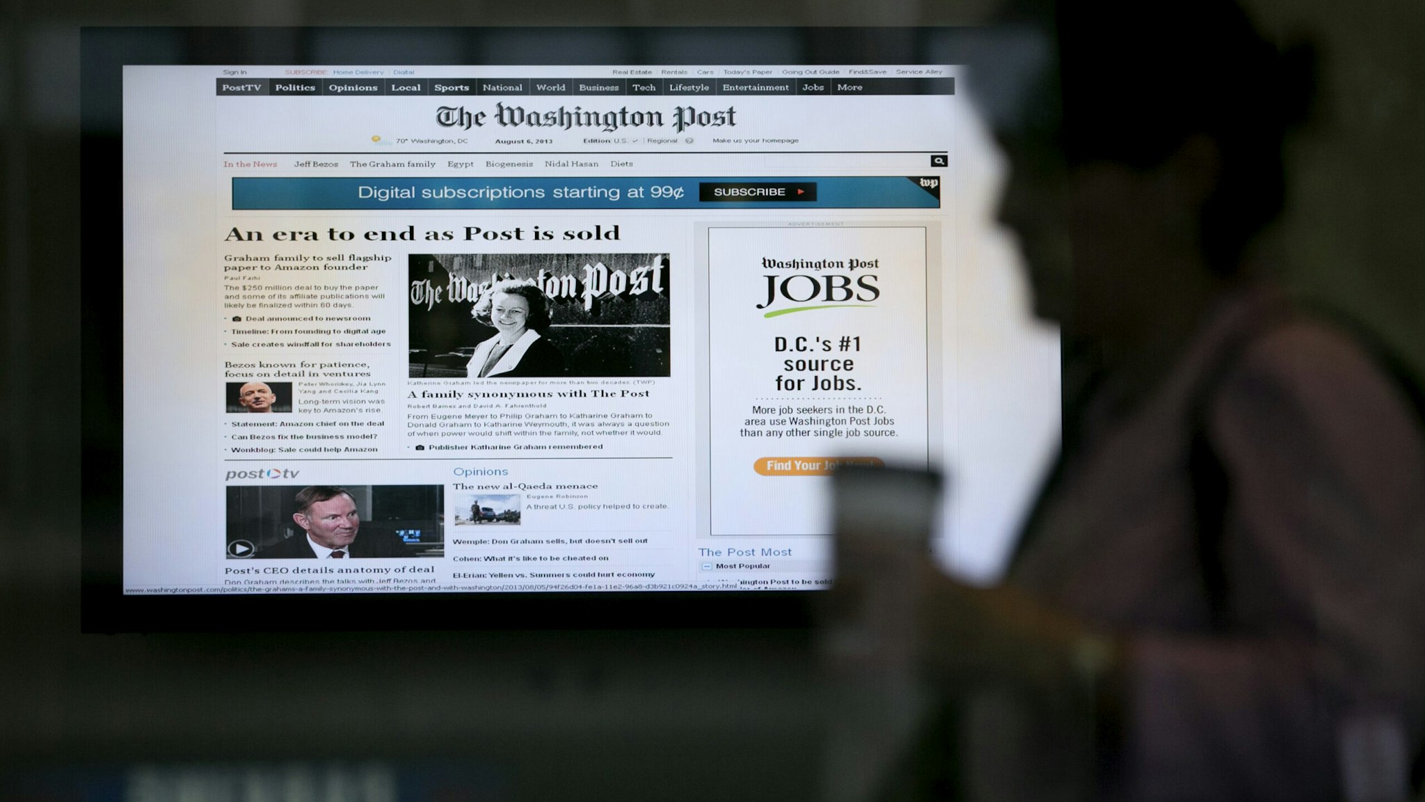 A woman walks past a monitor displaying news that the owners of the Washington Post are to sell the newspaper to billionaire Jeff Bezos inside the Washington Post Co. headquarters in Washington, D.C., U.S., on Tuesday, Aug. 6, 2013. Amazon.com Inc. Chief Executive Officer Jeff Bezos agreed to buy the Washington Post for $250 million, betting that he can apply his success in e-commerce to the struggling newspaper industry.