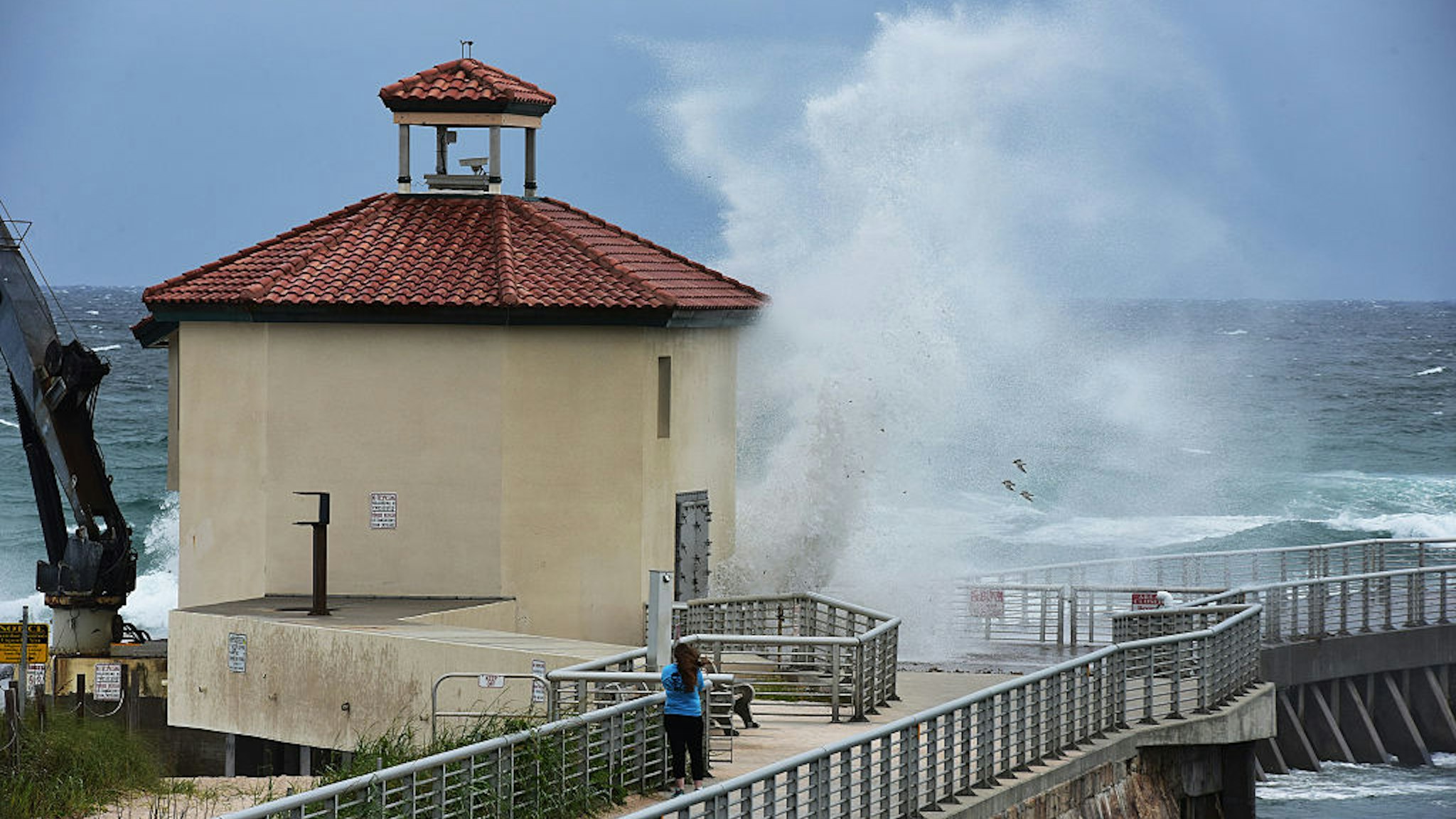 A woman takes pictures as Hurricane Matthew lashes the Boynton Beach inlet with high winds and waves as it makes its way toward South Florida Thursday, Oct. 6, 2016 in Boynton Beach, Fla.