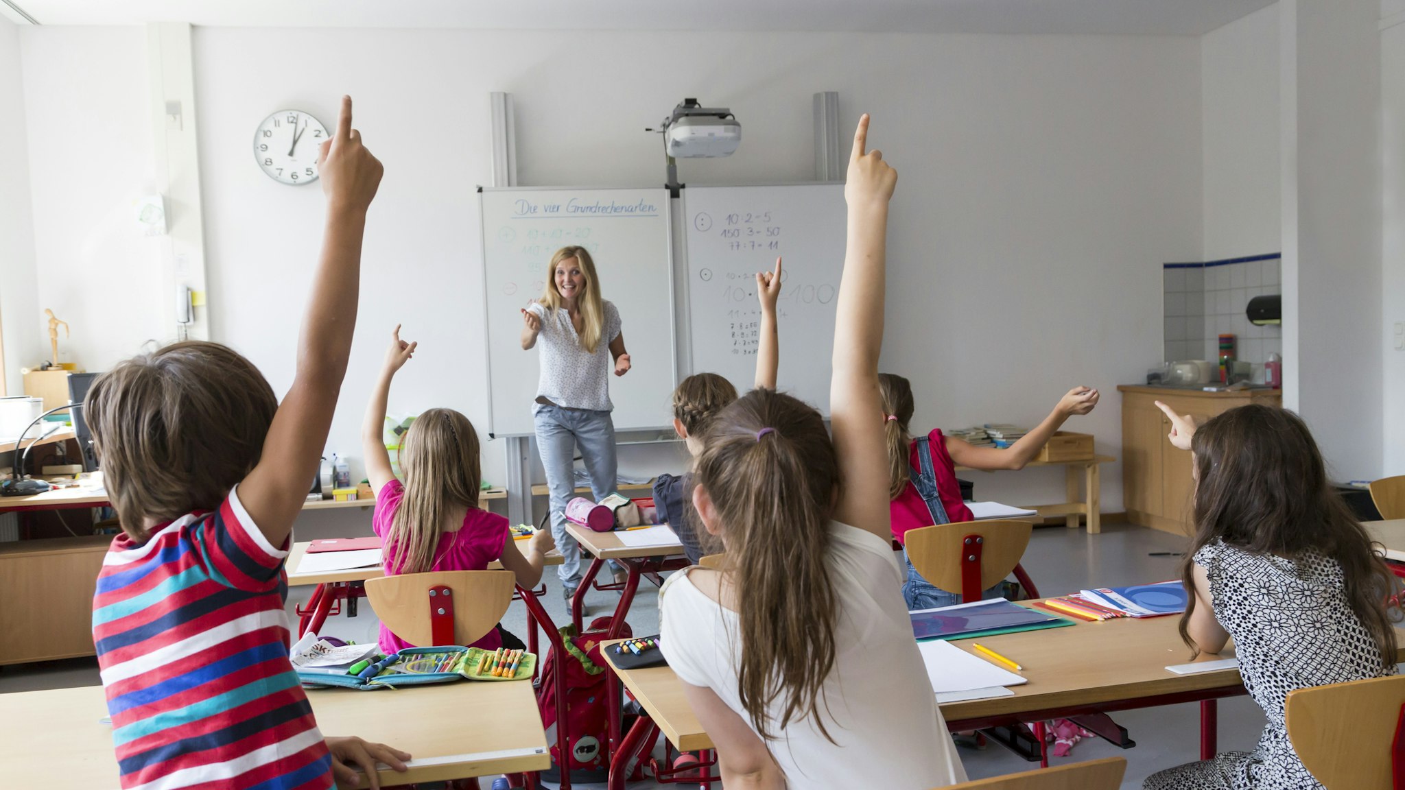 Active pupils raising their hands in class - stock photo