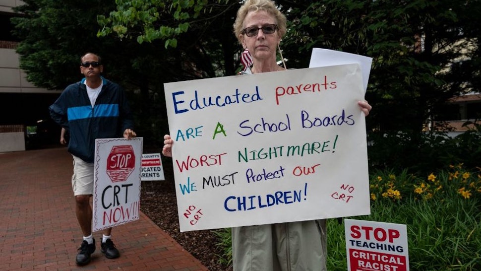 People hold up signs during a rally against "critical race theory" (CRT) being taught in schools at the Loudoun County Government center in Leesburg, Virginia on June 12, 2021. - "Are you ready to take back our schools?" Republican activist Patti Menders shouted at a rally opposing anti-racism teaching that critics like her say trains white children to see themselves as "oppressors." "Yes!", answered in unison the hundreds of demonstrators gathered this weekend near Washington to fight against "critical race theory," the latest battleground of America's ongoing culture wars. The term "critical race theory" defines a strand of thought that appeared in American law schools in the late 1970s and which looks at racism as a system, enabled by laws and institutions, rather than at the level of individual prejudices. But critics use it as a catch-all phrase that attacks teachers' efforts to confront dark episodes in American history, including slavery and segregation, as well as to tackle racist stereotypes. (Photo by ANDREW CABALLERO-REYNOLDS / AFP) (Photo by