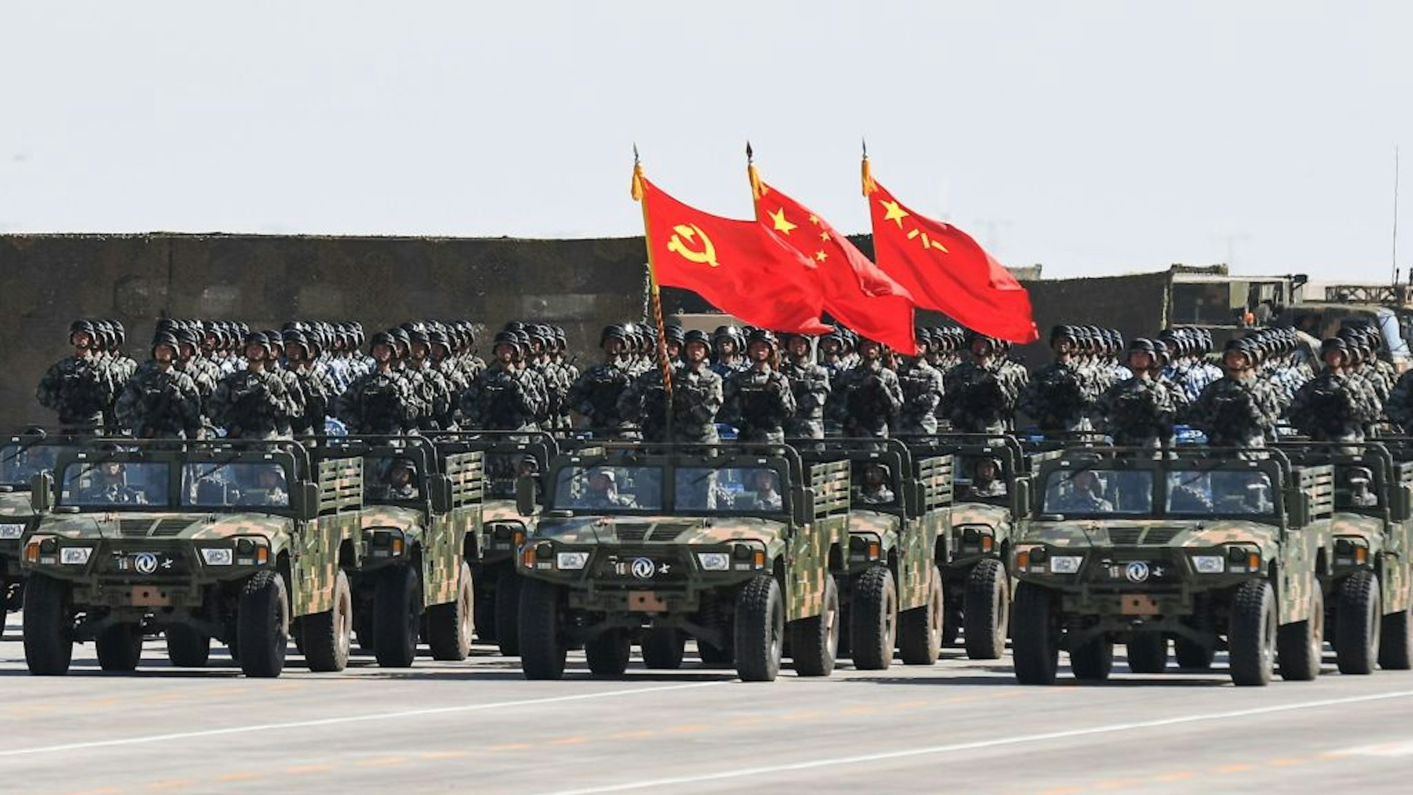 Chinese soldiers carry the flags of (L to R) the Communist Party, the state, and the People's Liberation Army during a military parade at the Zhurihe training base in China's northern Inner Mongolia region on July 30, 2017. China held a parade of its armed forces on July 30 to mark the 90th anniversary of the People's Liberation Army (PLA) in a display of military might. / AFP PHOTO / STR / China OUT
