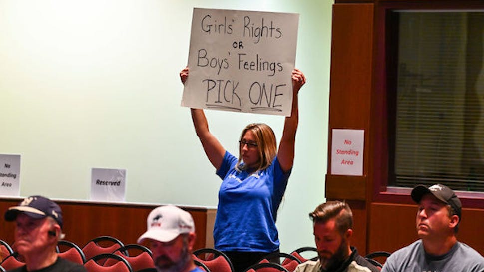 ASHBURN, VA – AUGUST 11: A woman holds a sign as Loudoun County