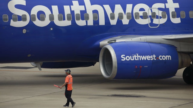 A worker directs a Southwest Airlines Co. Boeing 737 passenger jet pushing back from a gate at Midway International Airport (MDW) in Chicago, Illinois, U.S., on Monday, Oct. 11, 2021. Southwest Airlines Co. disruptions moved into a fourth day, with 355 canceled flights, or 10% of its daily schedule, on Monday, the latest in a series of setbacks at the carrier. 