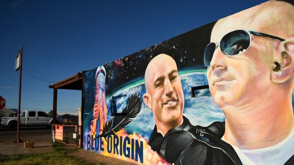 TOPSHOT - A pickup truck drives past a mural of billionaire Amazon founder Jeff Bezos (R) and his brother Mark Bezos with a Blue Origin rocket in Van Horn, Texas on October 11, 2021. - Blue Origin is scheduled to launch the New Shepard NS-18 mission to space with passengers including actor William Shatner on October 13 from West Texas, near Van Horn. (Photo by Patrick T. FALLON / AFP) (Photo by