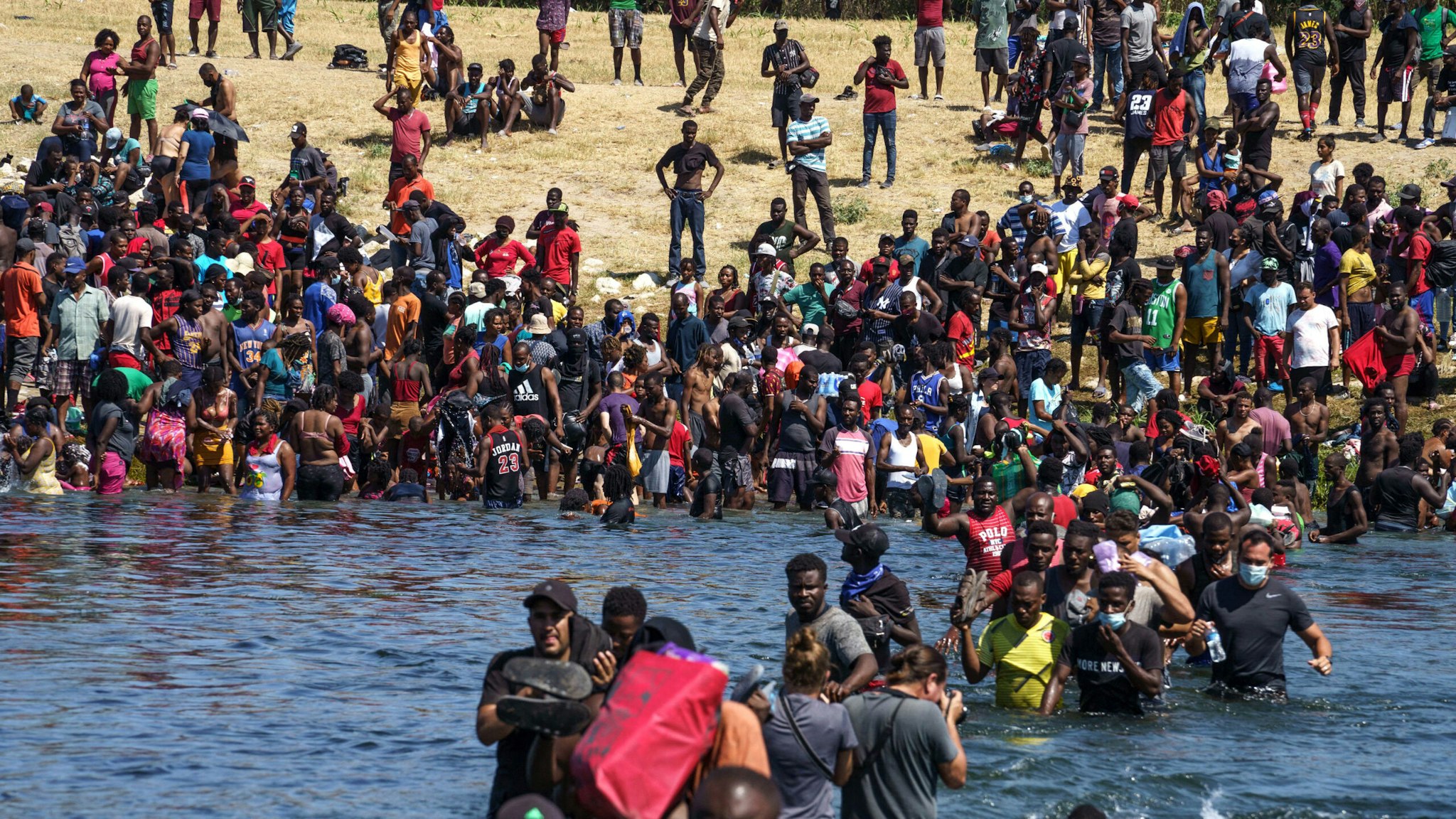 Haitian migrants, part of a group of over 10,000 people staying in an encampment on the US side of the border, cross the Rio Grande river to get food and water in Mexico, after another crossing point was closed near the Acuna Del Rio International Bridge in Del Rio, Texas on September 19, 2021. - The United States said Saturday it would ramp up deportation flights for thousands of migrants who flooded into the Texas border city of Del Rio, as authorities scramble to alleviate a burgeoning crisis for President Joe Biden's administration.