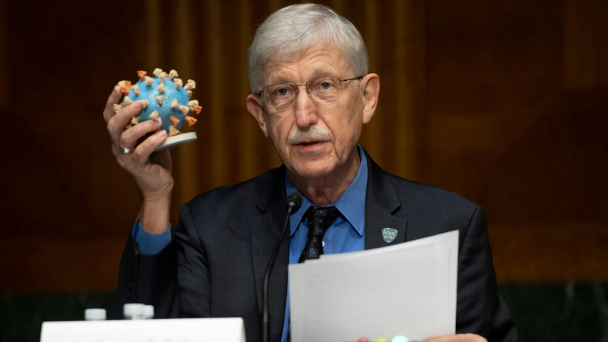 Dr. Francis Collins, Director of the National Institutes of Health (NIH), holds up a model of COVID-19, known as coronavirus, during a US Senate Appropriations subcommittee hearing on the plan to research, manufacture and distribute a coronavirus vaccine, known as Operation Warp Speed, July 2, 2020 on Capitol Hill in Washington, DC.