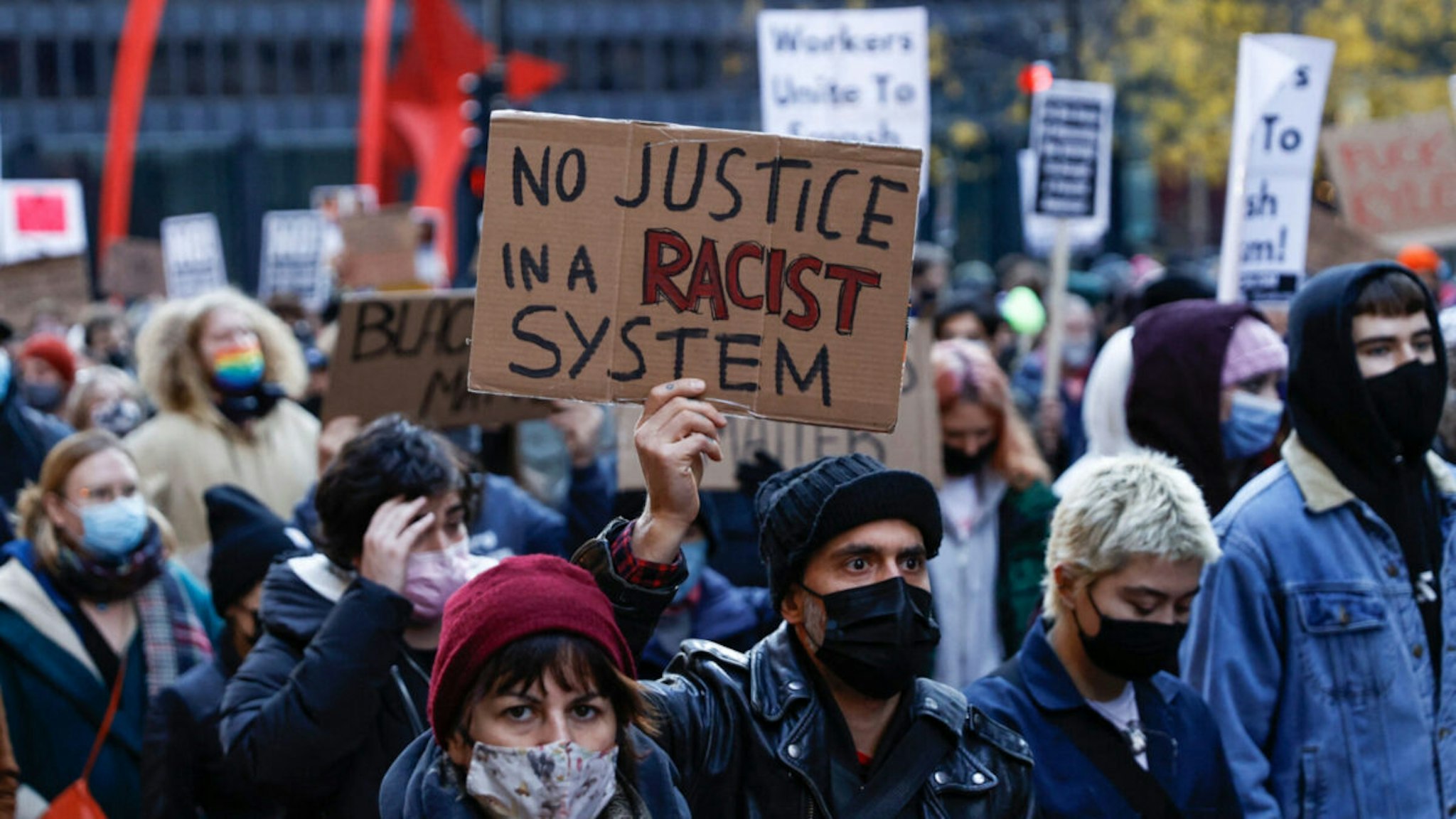 Demonstrators hold signs as they march during a protest against the not guilty verdit for Kyle Rittenhouse on Novermber 20, 2021 in Chicago, Illinois.