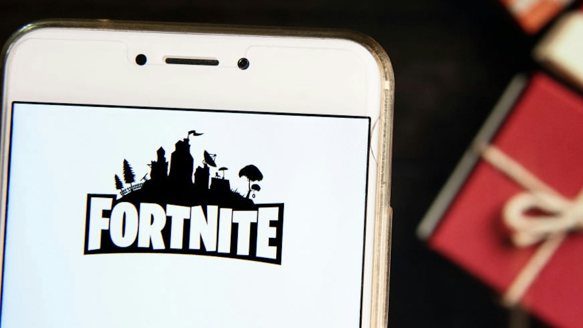 Online video game by Epic Games company Fortnite logo is HONG KONG - 2018/11/21: In this photo illustration, the Online video game by Epic Games company Fortnite logo is seen displayed on an Android mobile device with a Christmas wrapped gifts in the background. (Photo Illustration by Miguel Candela/SOPA Images/LightRocket via Getty Images) SOPA Images / Contributor