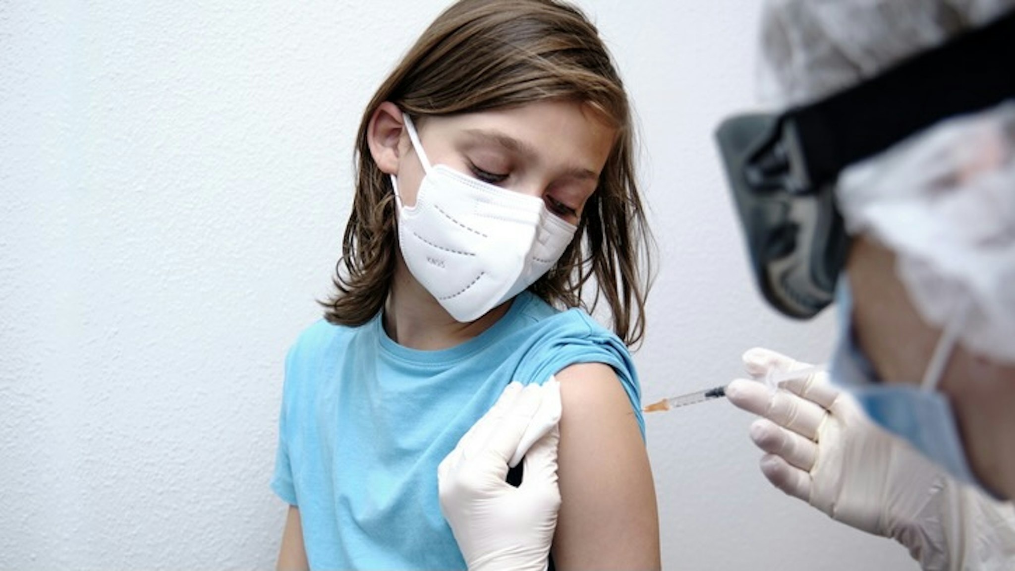 Female doctor giving covid-19 vaccine to a boy - stock photo Roberto Jimenez Mejias