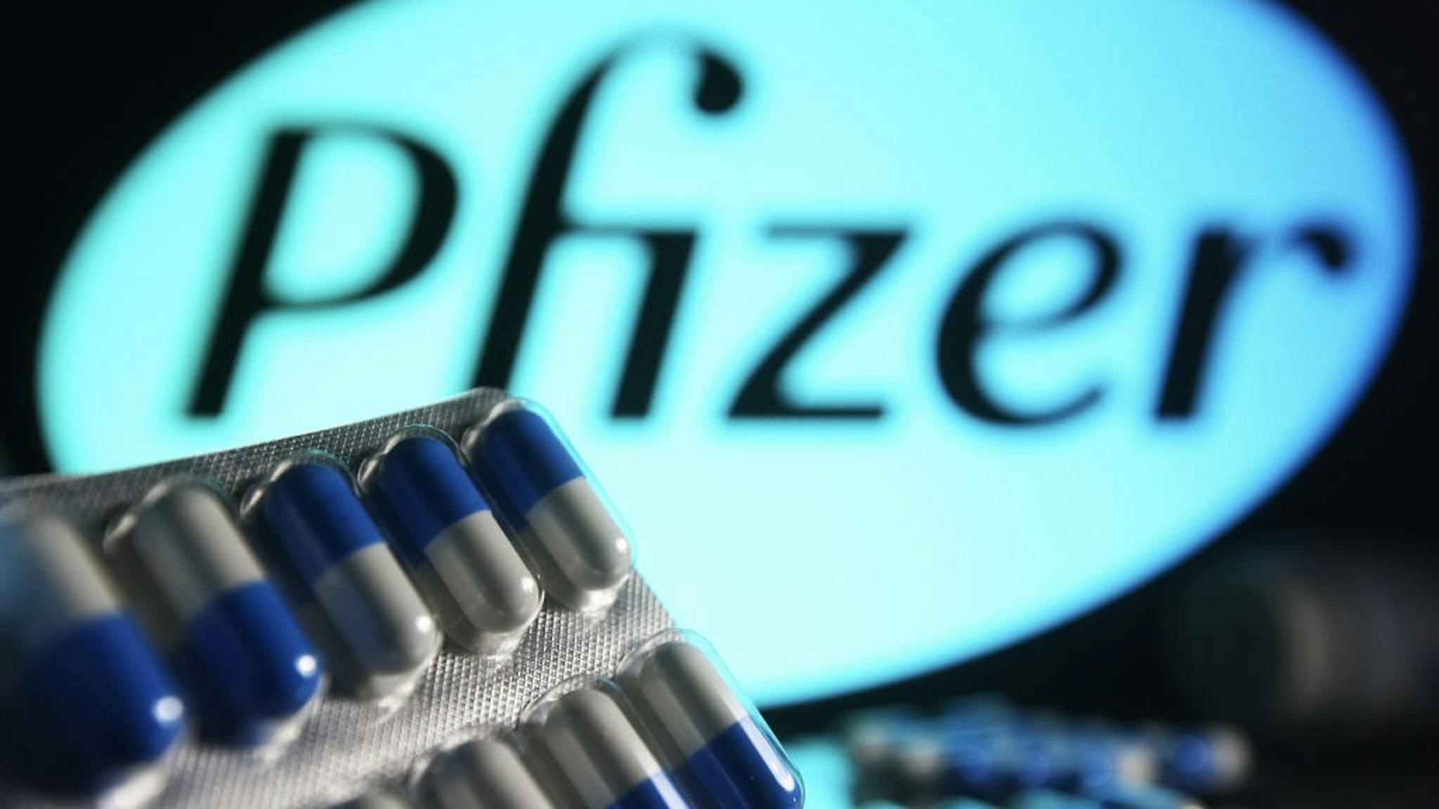 In this photo illustration, medicine pills are seen on... UKRAINE - 2021/10/16: In this photo illustration, medicine pills are seen on display with a Pfizer logo in the background. (Photo Illustration by Pavlo Gonchar/SOPA Images/LightRocket via Getty Images) SOPA Images / Contributor