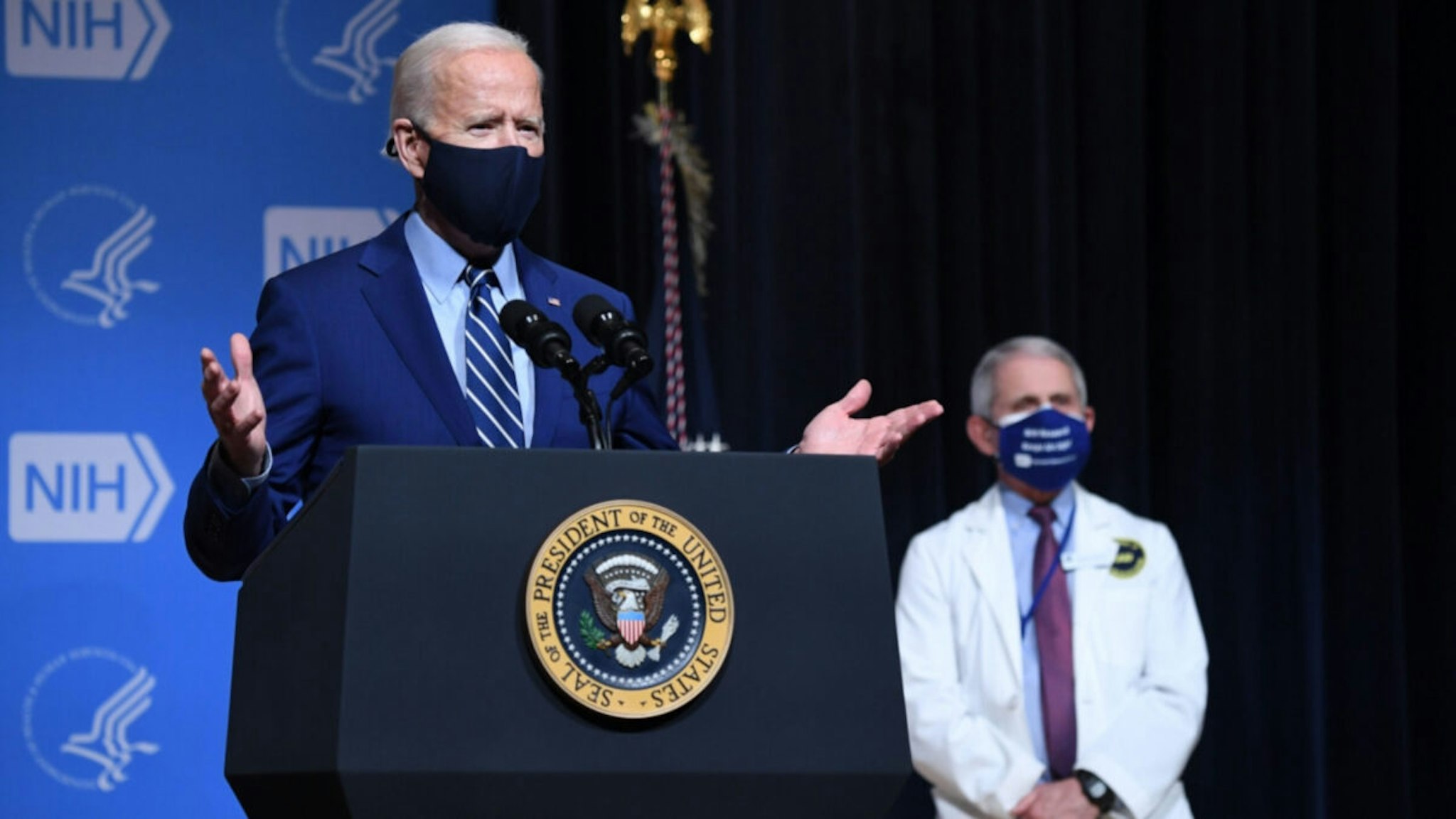 US President Joe Biden speaks, flanked by White House Chief Medical Adviser on Covid-19 Dr. Anthony Fauci (R) during a visit to the National Institutes of Health (NIH) in Bethesda, Maryland, February 11, 2021.